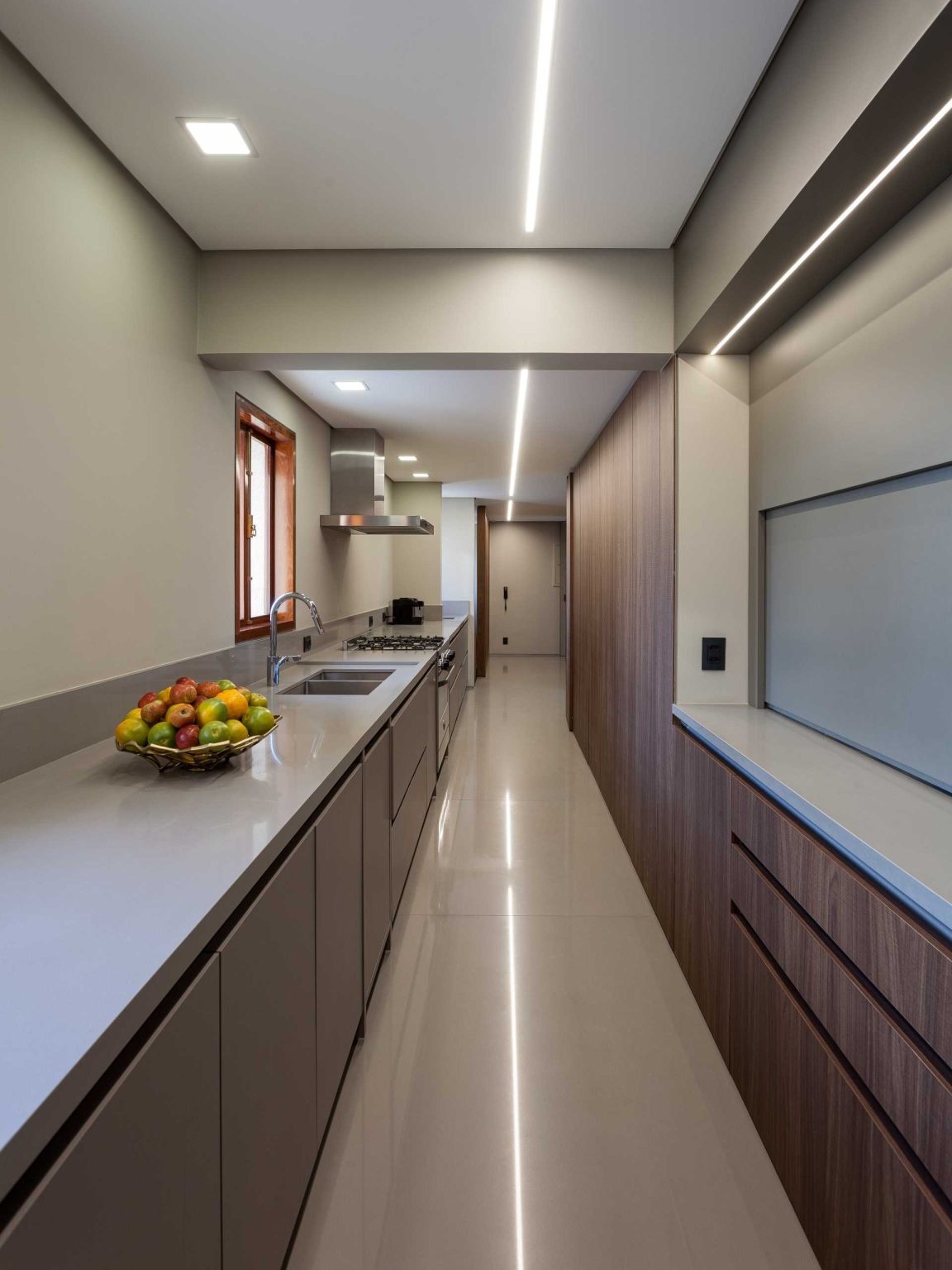 This long contemporary kitchen combines luxury finishes with practical planning. A clever pass-through window links the kitchen, pantry, and dining room for seamless entertaining.