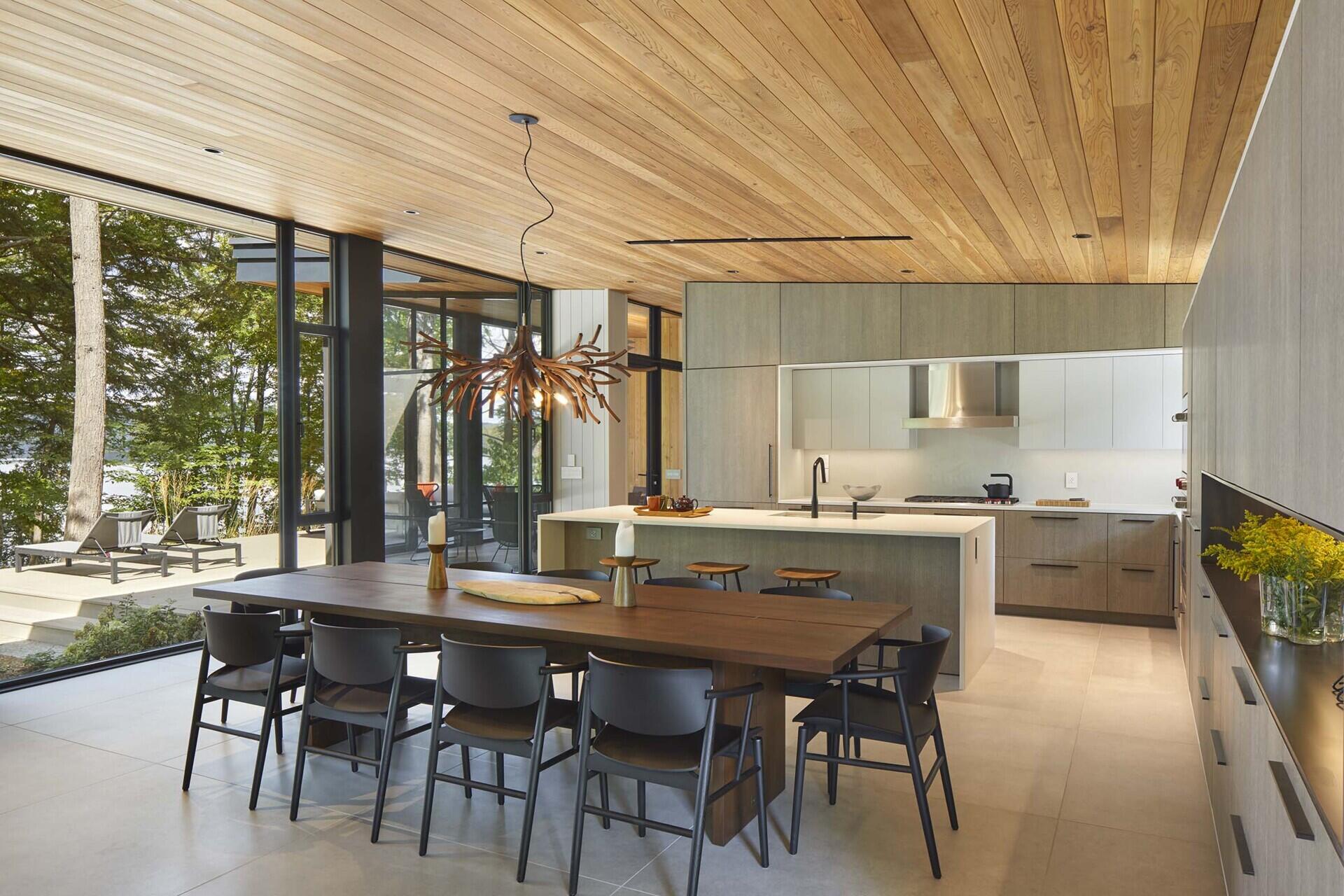 The kitchen, with its pale wood and white cabinetry, and matching island, is integrated into the central great room alongside the living and dining areas.