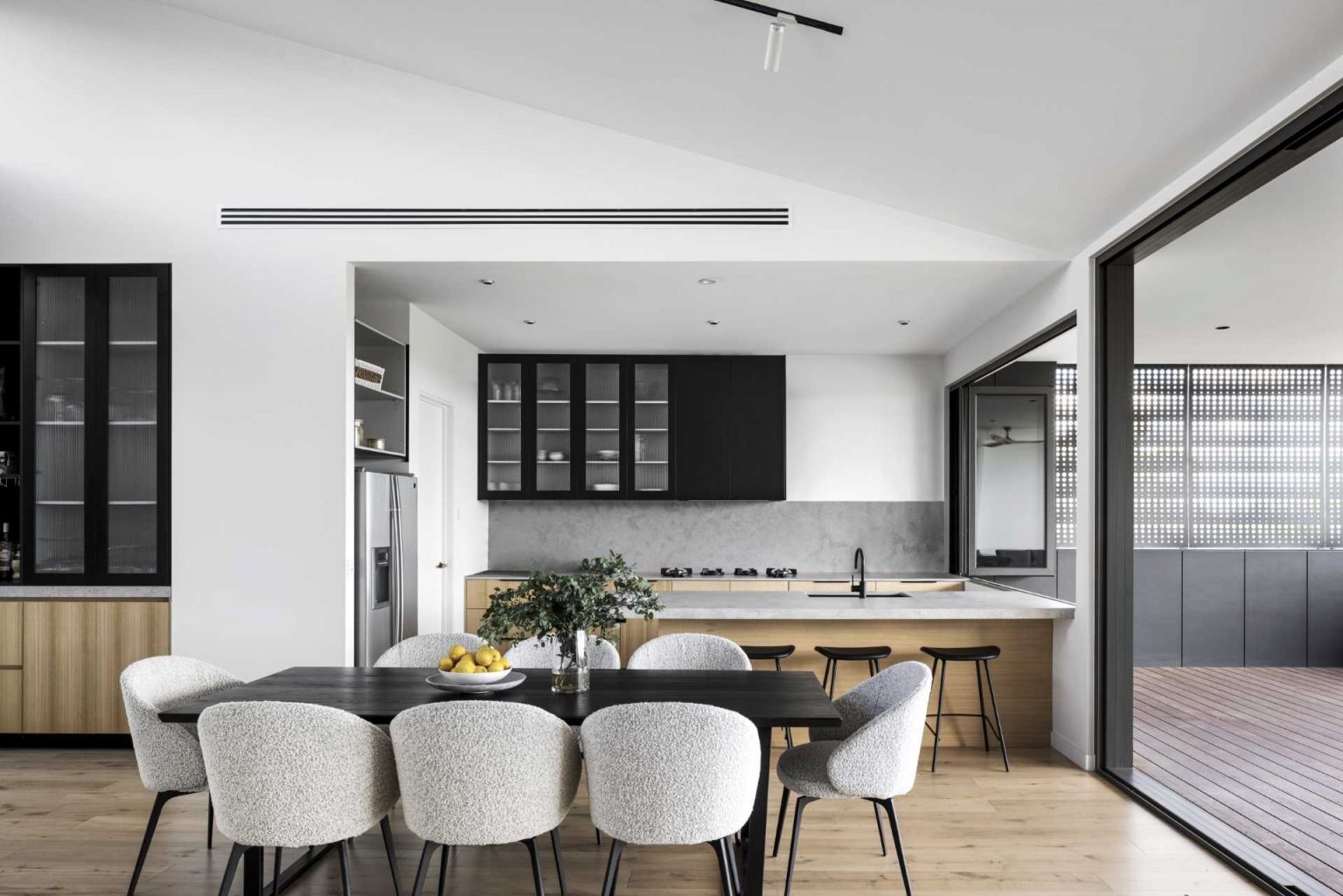A wood-burning fireplace, timber flooring, and bushland views make this open-plan living space both welcoming and visually impressive.