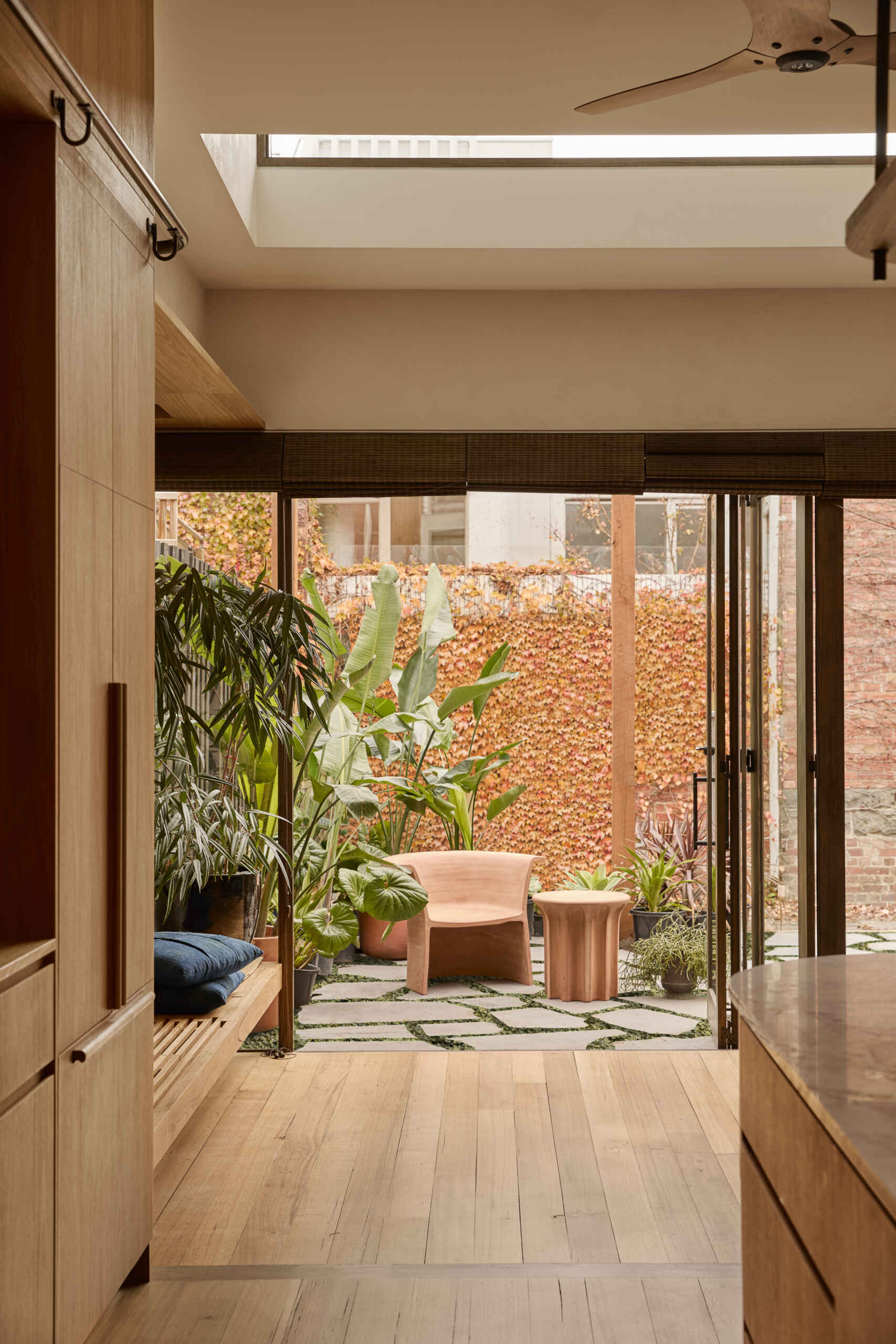 A lush courtyard garden with tropical planting, opening directly from a modern kitchen in a heritage terrace home.