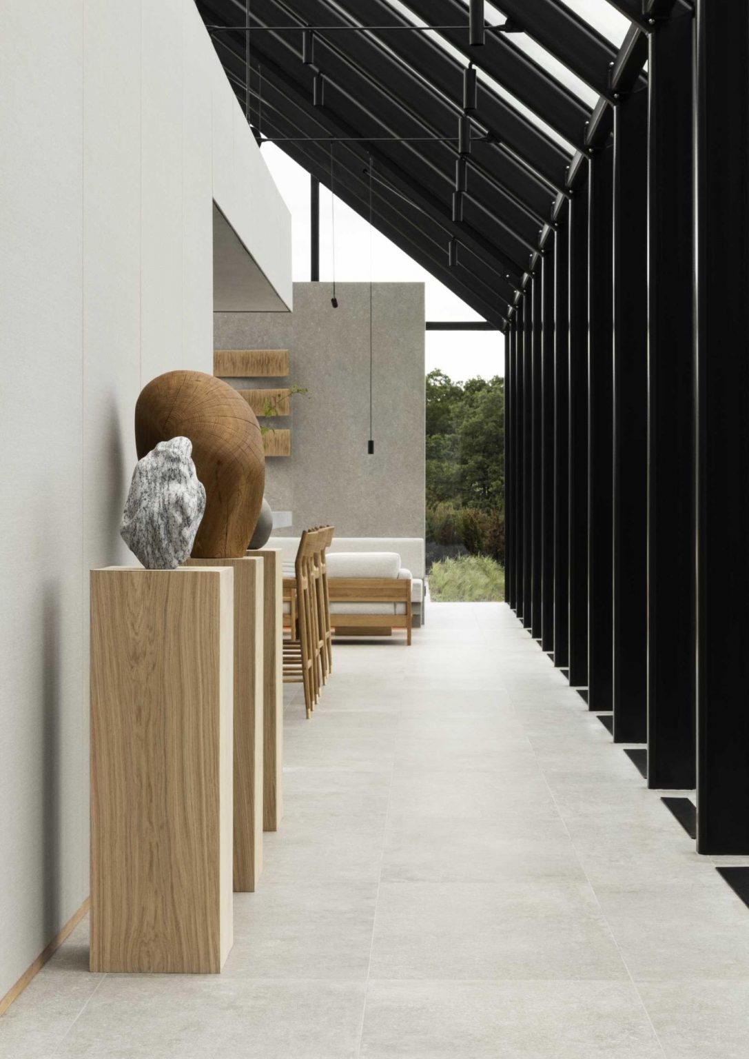 El restaurante del pabellón de cristal presenta marcos internos expuestos y pisos de piedra, creando un umbral perfecto entre el sitio y los espacios interiores.
