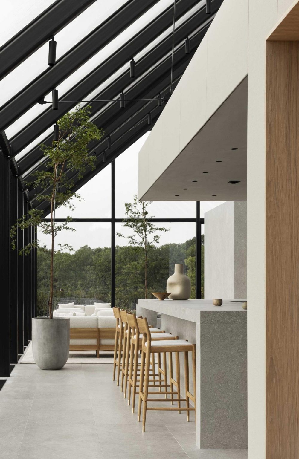 El restaurante del pabellón de cristal presenta marcos internos expuestos y pisos de piedra, creando un umbral perfecto entre el sitio y los espacios interiores.