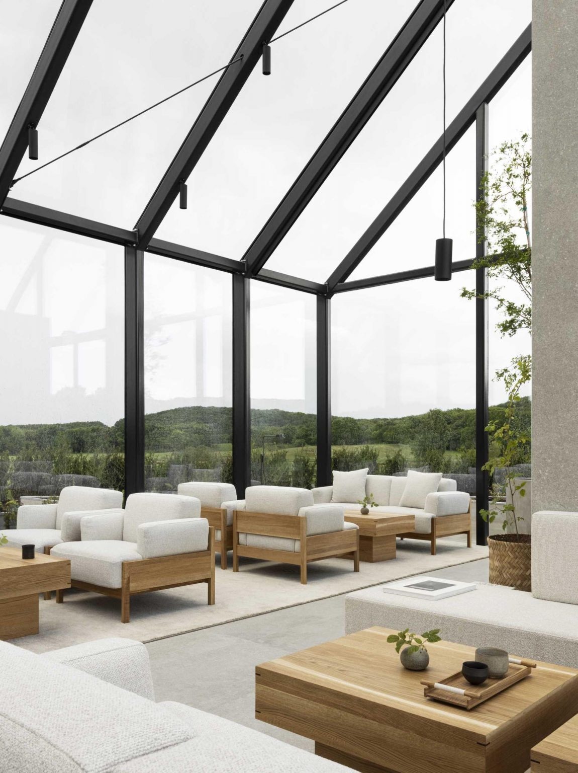 El restaurante del pabellón de cristal presenta marcos internos expuestos y pisos de piedra, creando un umbral perfecto entre el sitio y los espacios interiores.