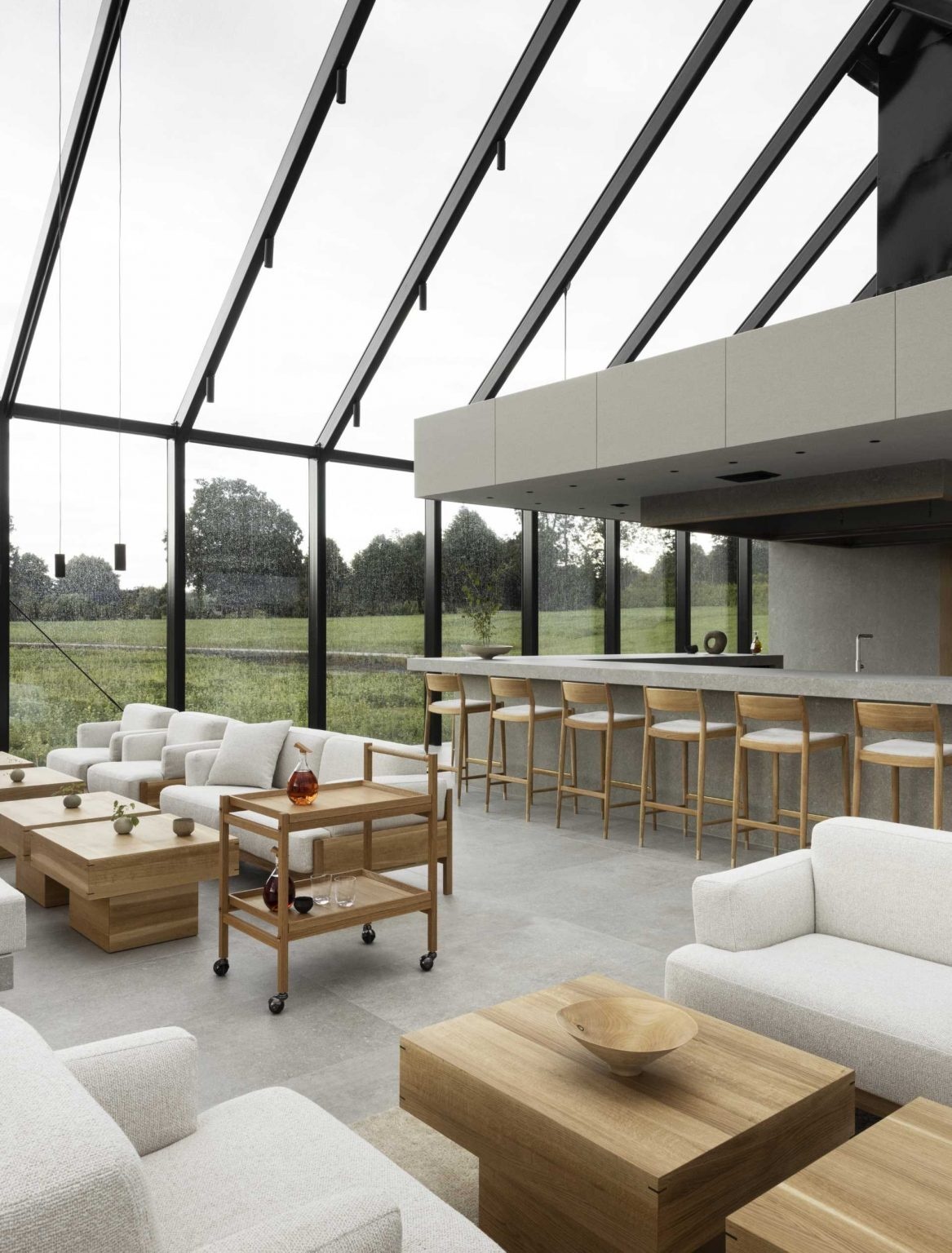 El restaurante del pabellón de cristal presenta marcos internos expuestos y pisos de piedra, creando un umbral perfecto entre el sitio y los espacios interiores.