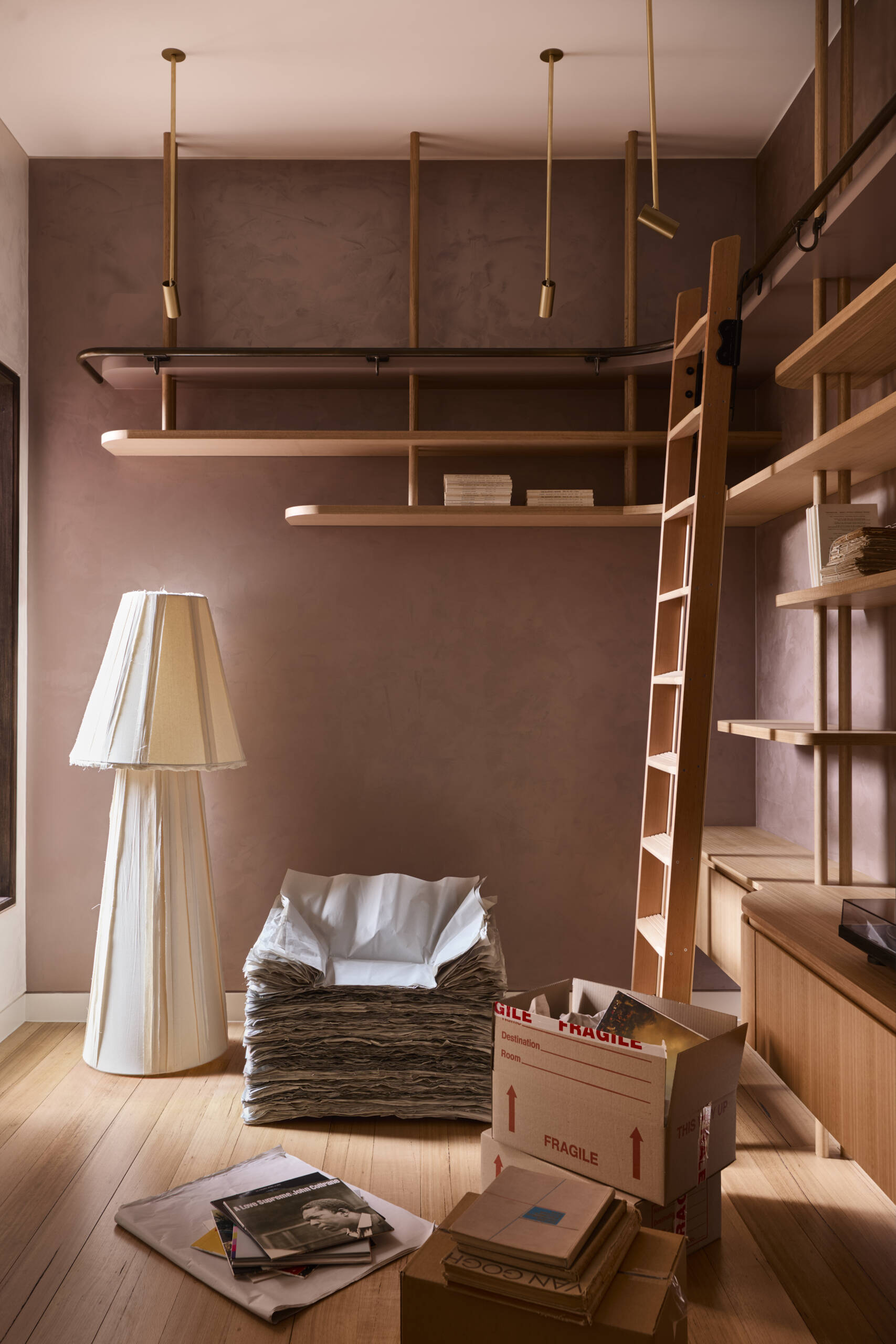 A warm and welcoming entry with custom shelving, a rolling library ladder, soft plaster walls, and pale timber floors. This cozy reading nook is full of clever storage ideas and relaxed interior styling inspiration.