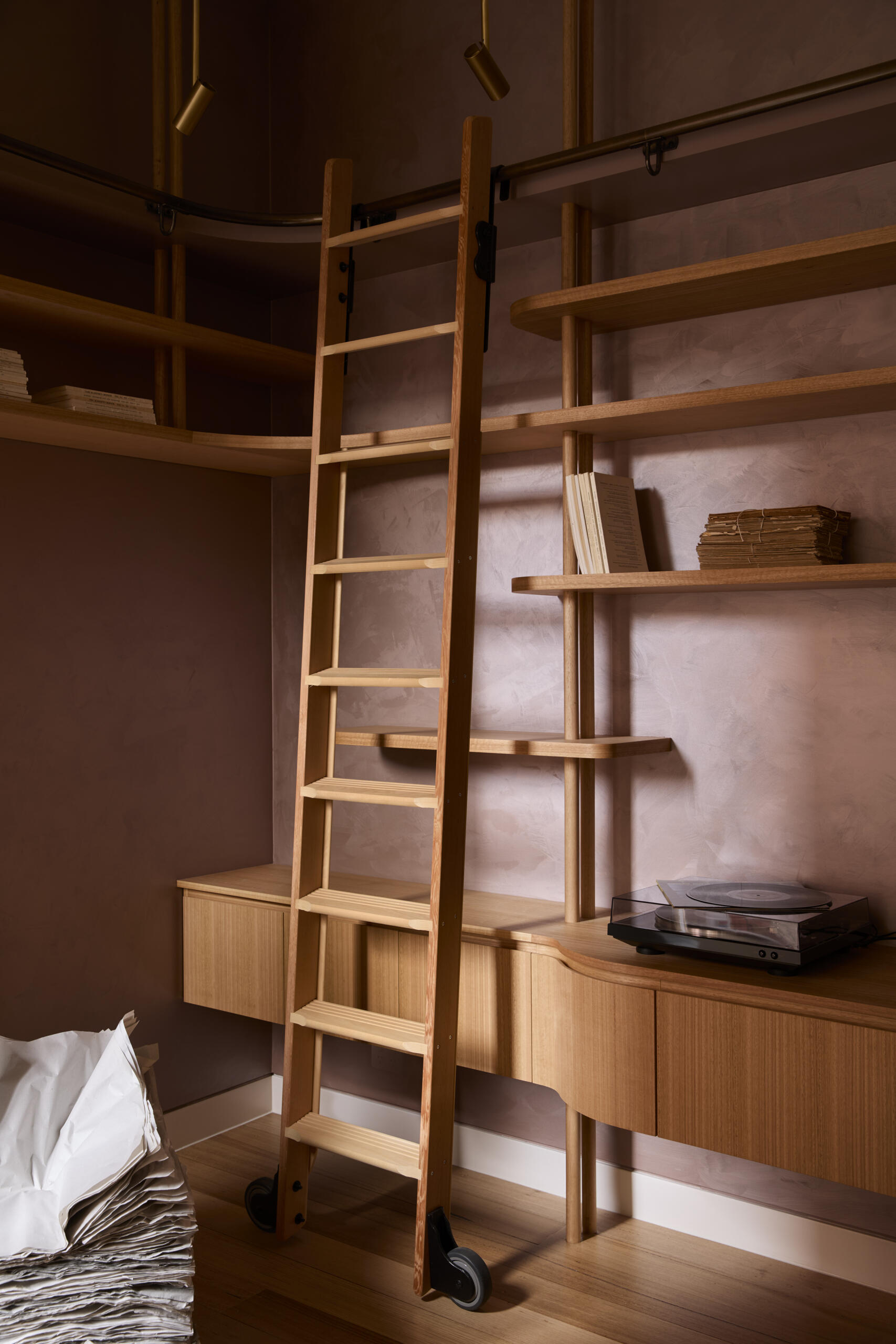 A warm and welcoming entry with custom shelving, a rolling library ladder, soft plaster walls, and pale timber floors. This cosy reading nook is full of clever storage ideas and relaxed interior styling inspiration.