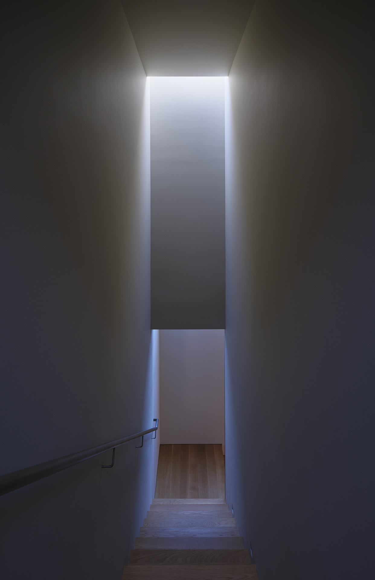 A modern staircase has natural light that shines from above.
