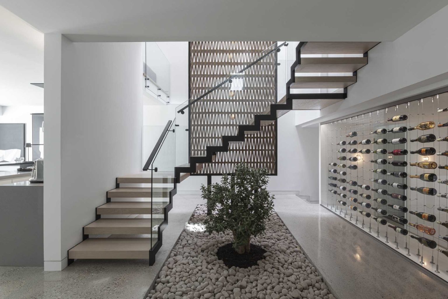 A dramatic quadruple-height staircase runs through the center of Stack House, drawing natural light from skylights above down to the basement while linking every level of the home.