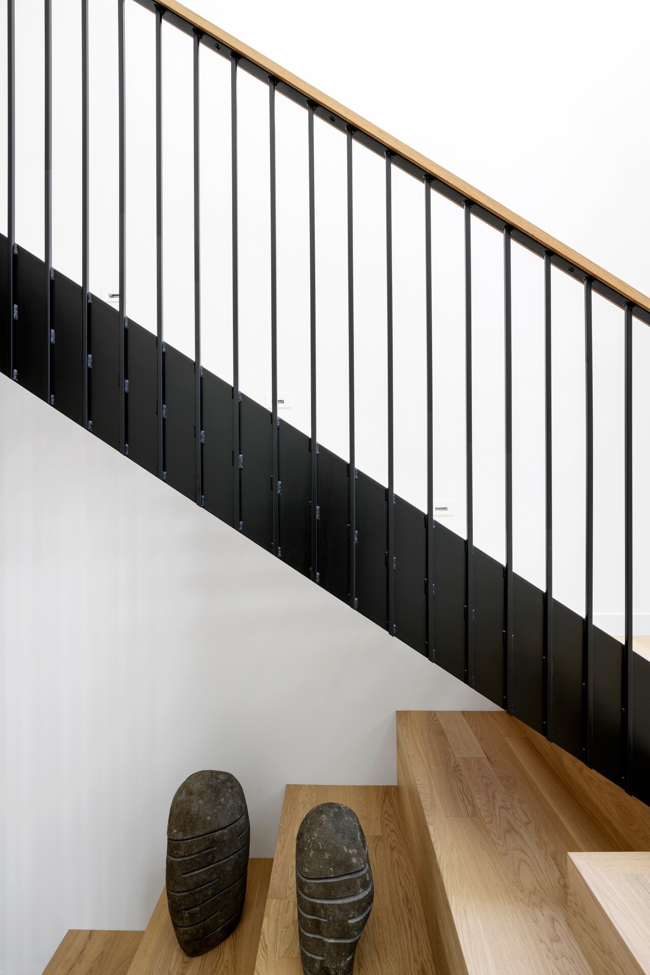 The staircase benefits from the home's double-height design, allowing daylight from above and the windows brightening both levels. It creates an open transition between floors while reinforcing the home's light-filled atmosphere.