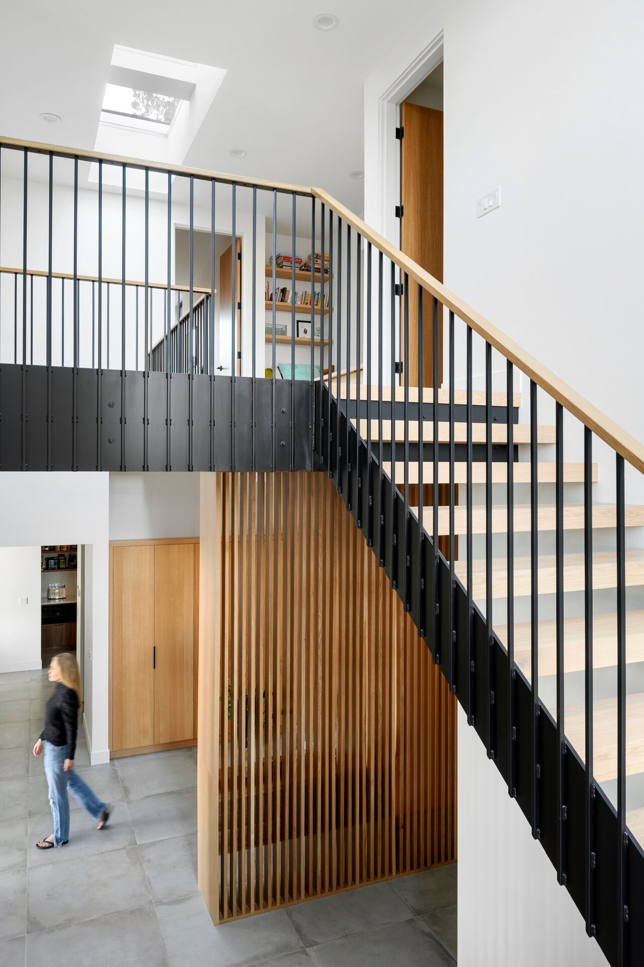 The staircase benefits from the home's double-height design, allowing daylight from above and the windows brightening both levels. It creates an open transition between floors while reinforcing the home's light-filled atmosphere.