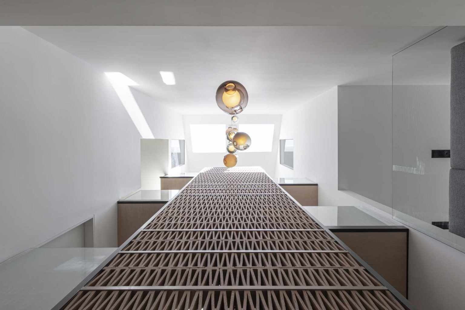 A dramatic quadruple-height staircase runs through the center of Stack House, drawing natural light from skylights above down to the basement while linking every level of the home.