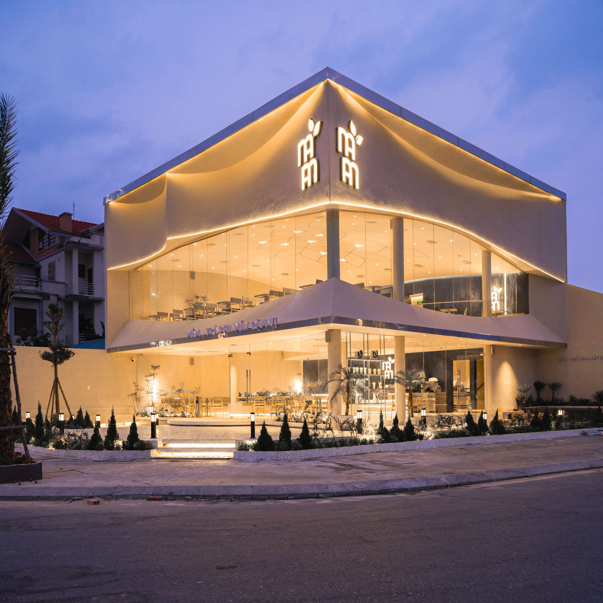 Inspired by the shape of a boat and featuring sweeping curved glass, soft flowing ceilings, and a calming neutral interior, this contemporary tea house celebrates one of Vietnam's most spectacular natural landscapes through architecture.