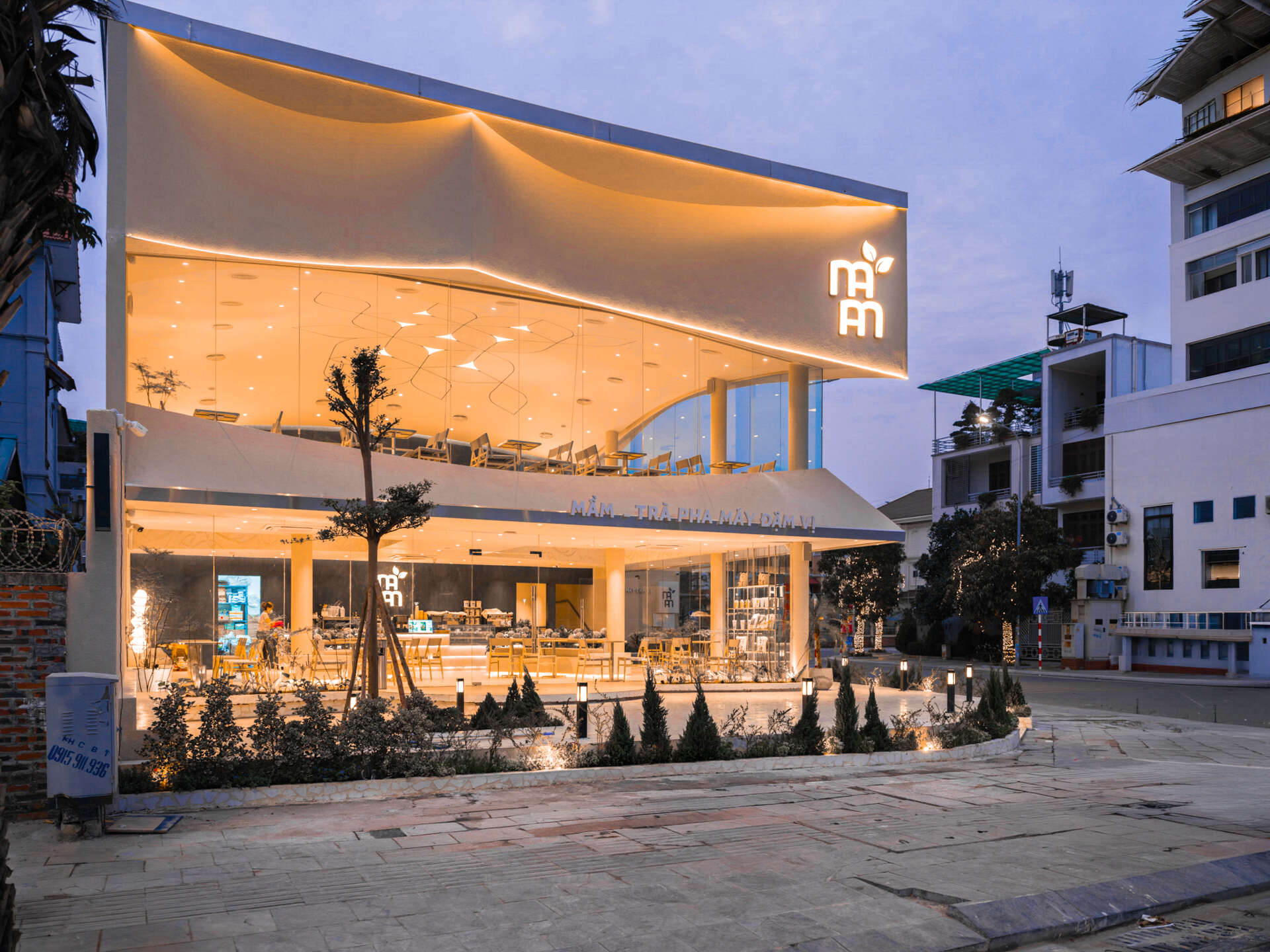 Inspired by the shape of a boat and featuring sweeping curved glass, soft flowing ceilings, and a calming neutral interior, this contemporary tea house celebrates one of Vietnam's most spectacular natural landscapes through architecture.