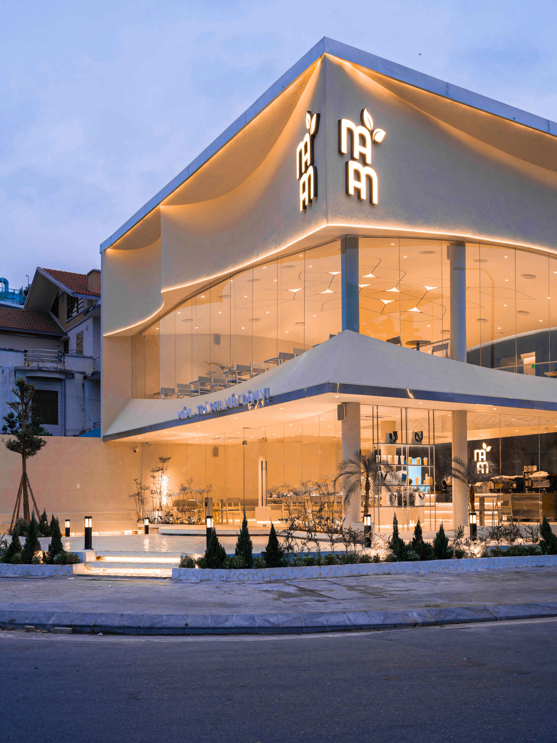 Inspired by the shape of a boat and featuring sweeping curved glass, soft flowing ceilings, and a calming neutral interior, this contemporary tea house celebrates one of Vietnam's most spectacular natural landscapes through architecture.