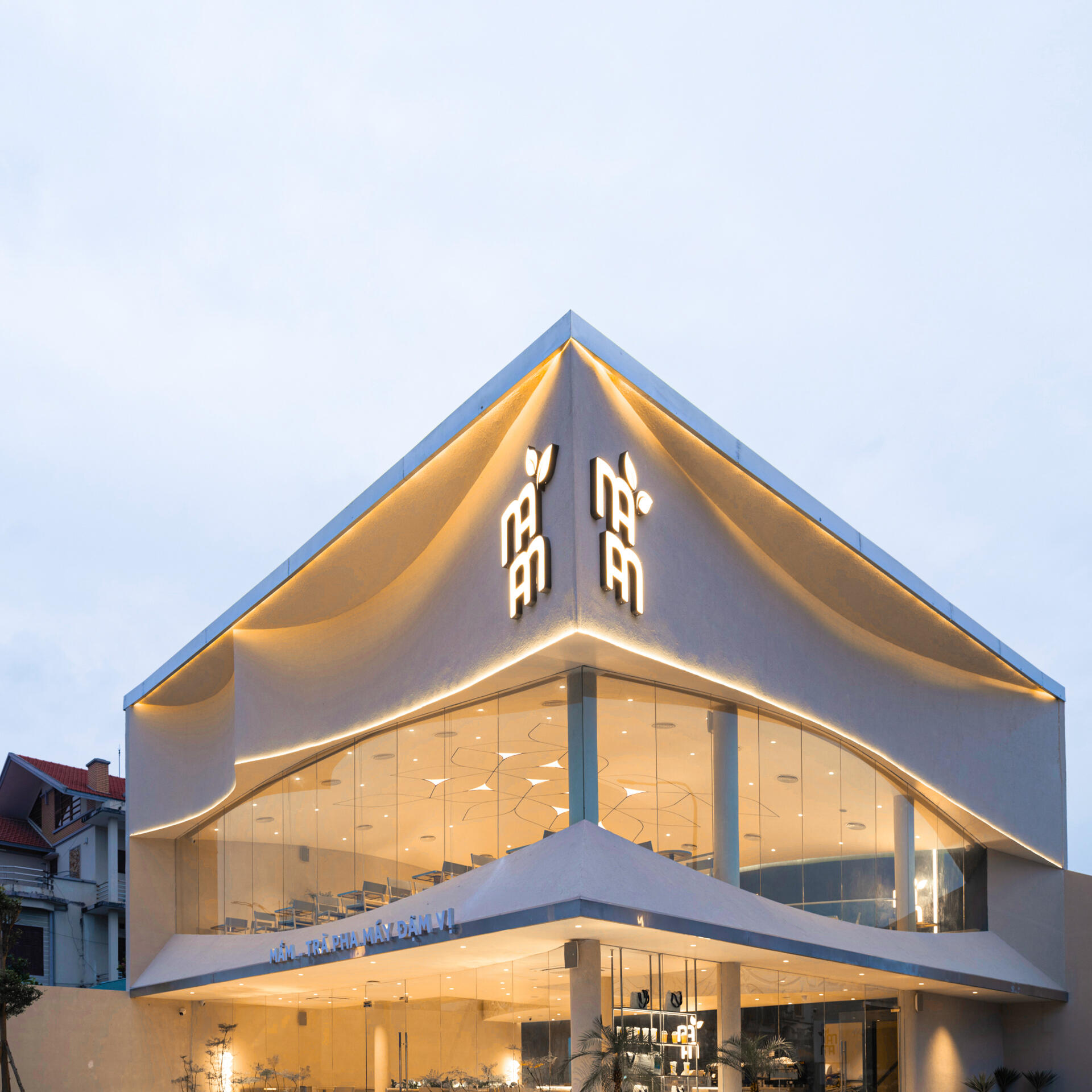 Inspired by the shape of a boat and featuring sweeping curved glass, soft flowing ceilings, and a calming neutral interior, this contemporary tea house celebrates one of Vietnam's most spectacular natural landscapes through architecture.