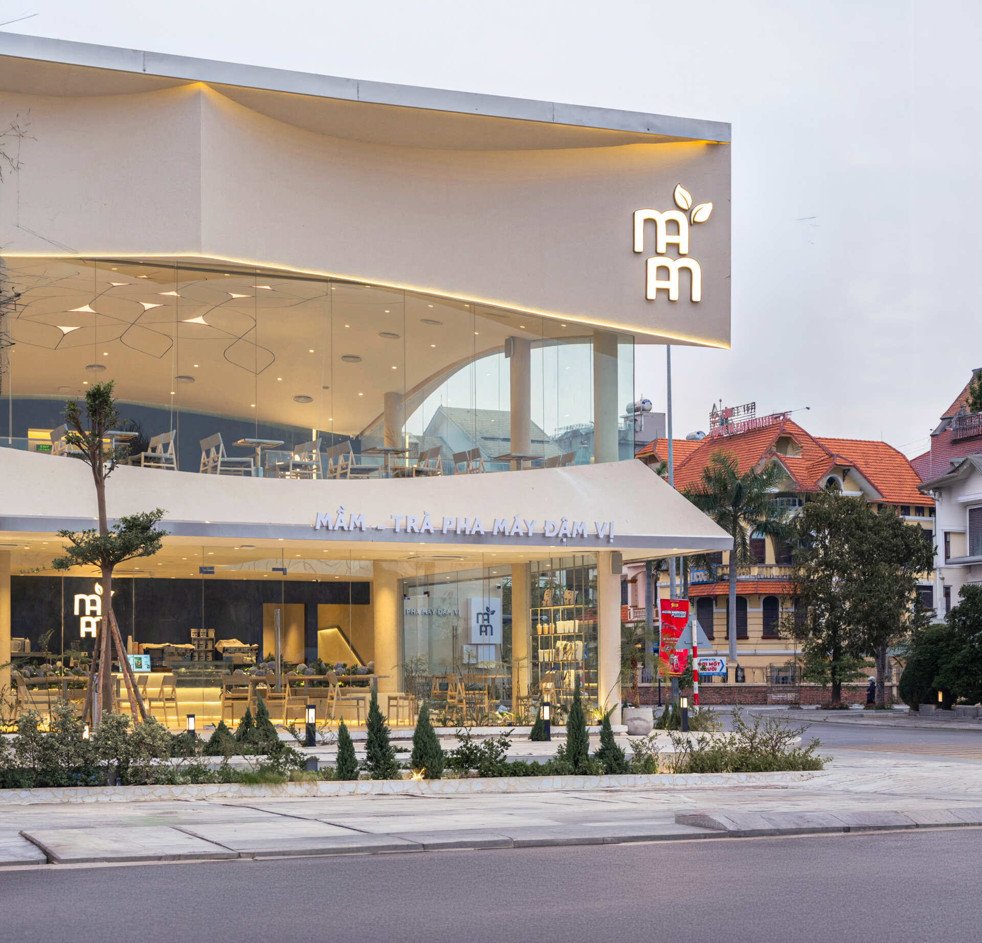 Inspired by the shape of a boat and featuring sweeping curved glass, soft flowing ceilings, and a calming neutral interior, this contemporary tea house celebrates one of Vietnam's most spectacular natural landscapes through architecture.