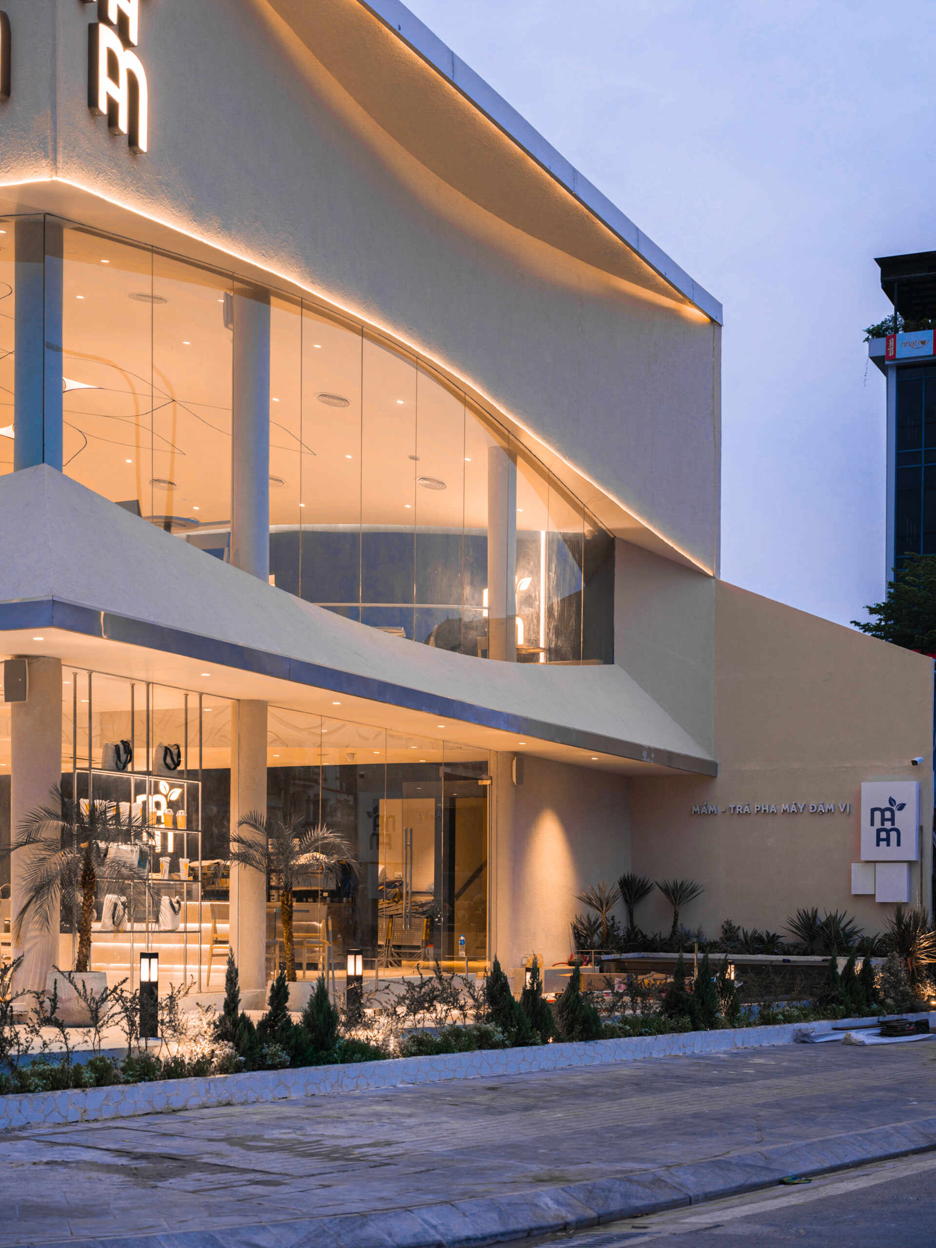 Inspired by the shape of a boat and featuring sweeping curved glass, soft flowing ceilings, and a calming neutral interior, this contemporary tea house celebrates one of Vietnam's most spectacular natural landscapes through architecture.