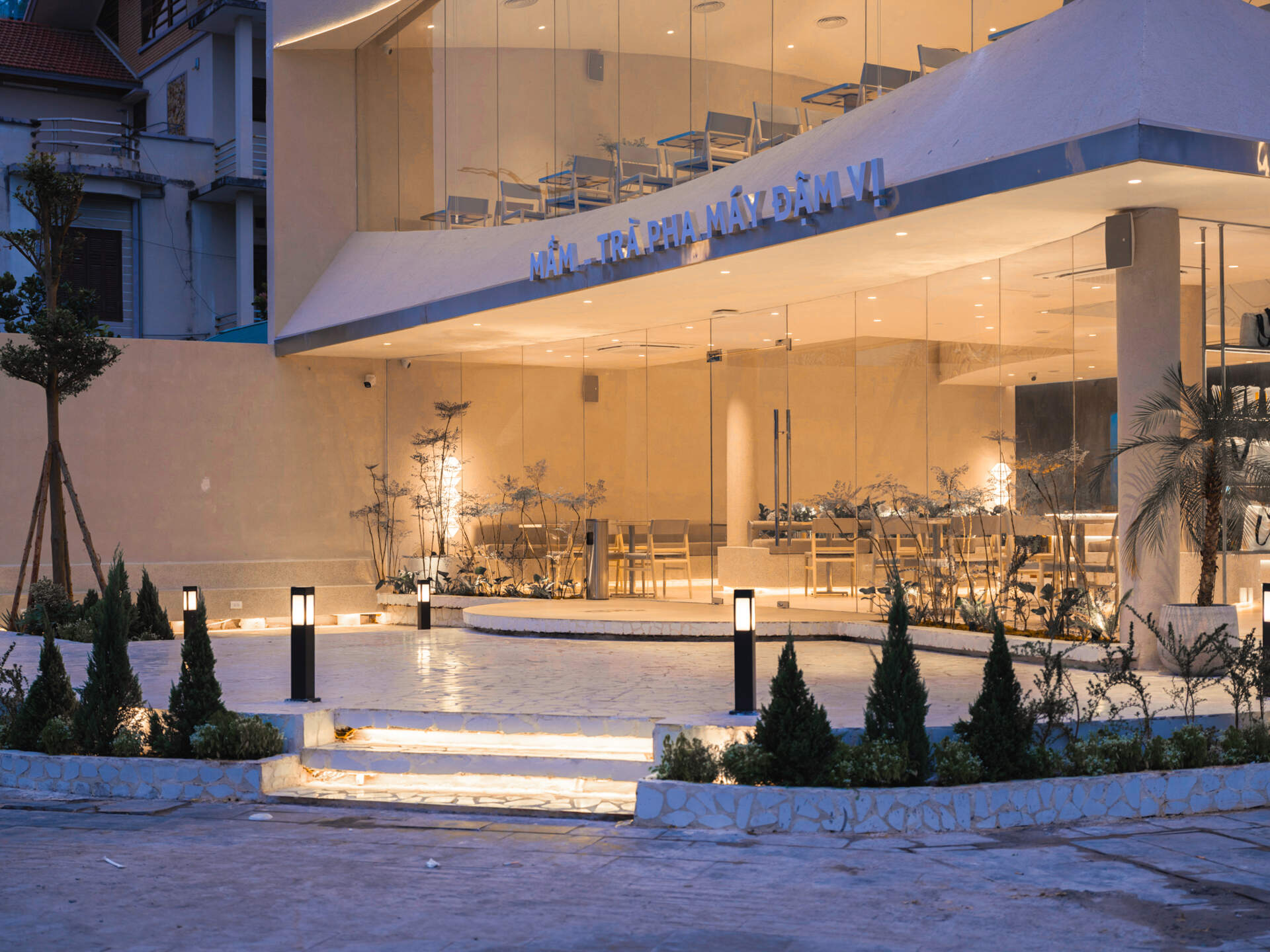 Inspired by the shape of a boat and featuring sweeping curved glass, soft flowing ceilings, and a calming neutral interior, this contemporary tea house celebrates one of Vietnam's most spectacular natural landscapes through architecture.