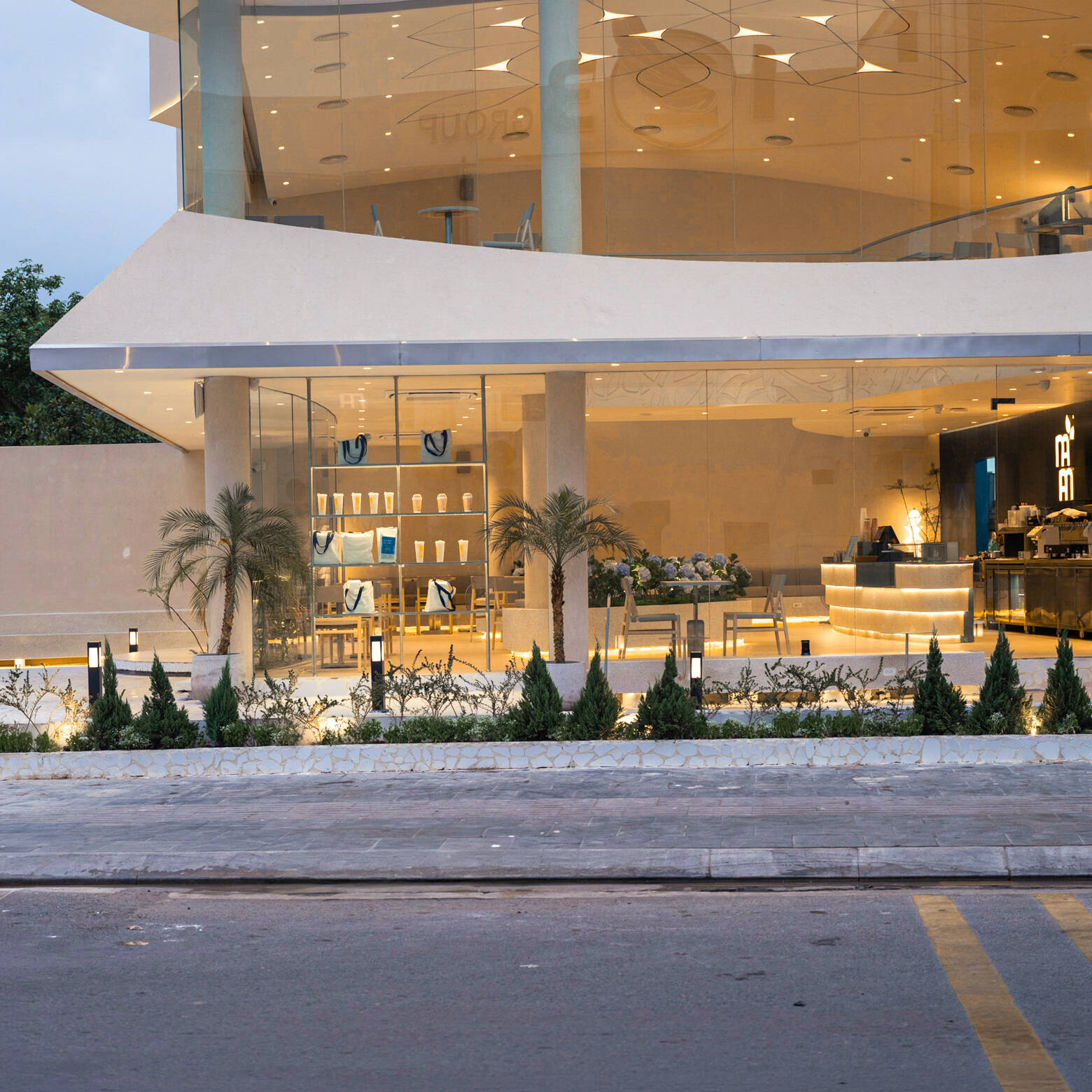 Inspired by the shape of a boat and featuring sweeping curved glass, soft flowing ceilings, and a calming neutral interior, this contemporary tea house celebrates one of Vietnam's most spectacular natural landscapes through architecture.