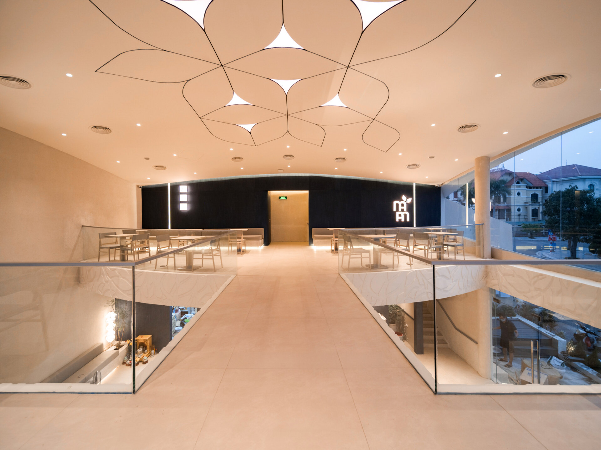 Inspired by the shape of a boat and featuring sweeping curved glass, soft flowing ceilings, and a calming neutral interior, this contemporary tea house celebrates one of Vietnam's most spectacular natural landscapes through architecture.