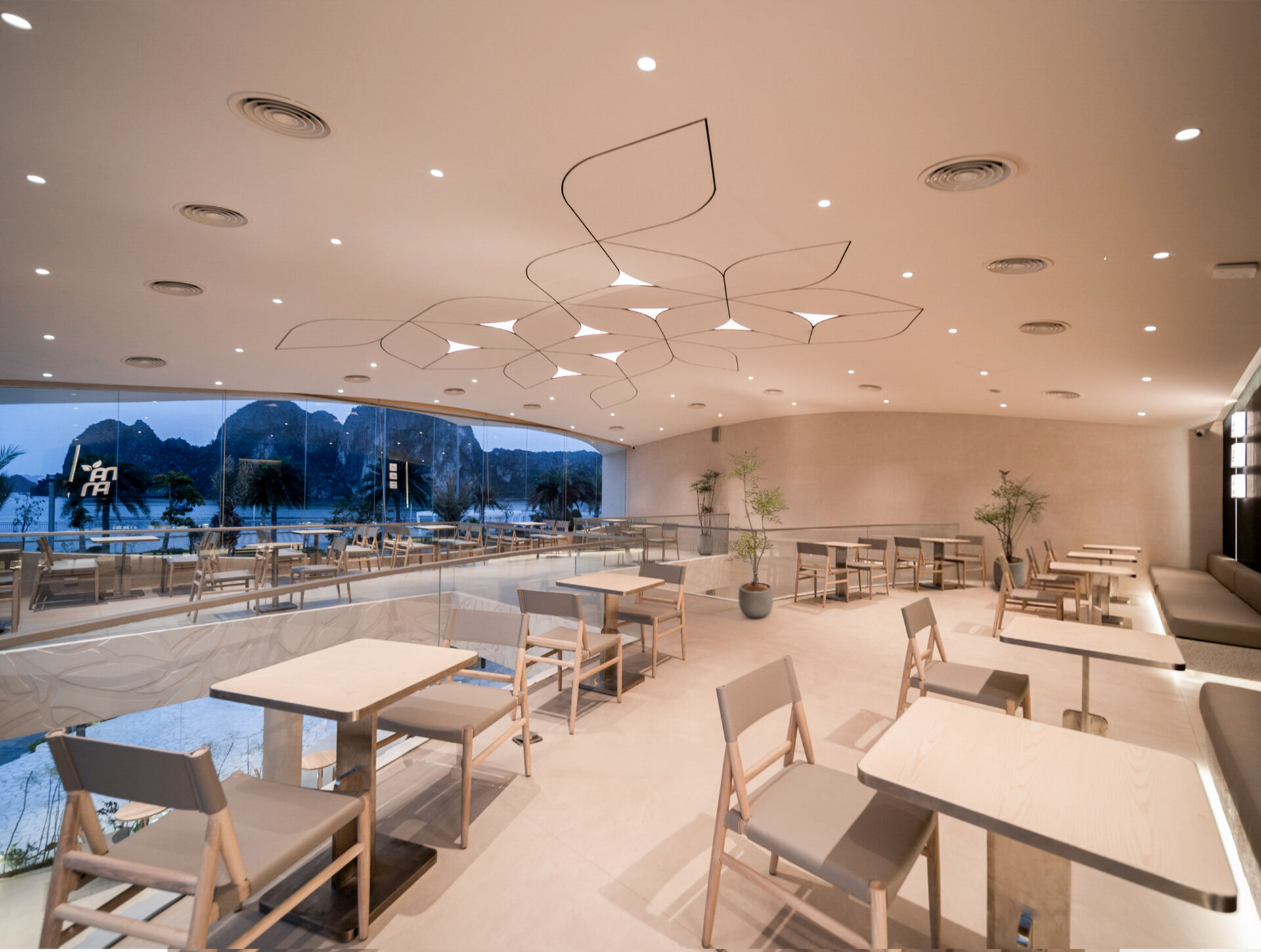 Inspired by the shape of a boat and featuring sweeping curved glass, soft flowing ceilings, and a calming neutral interior, this contemporary tea house celebrates one of Vietnam's most spectacular natural landscapes through architecture.