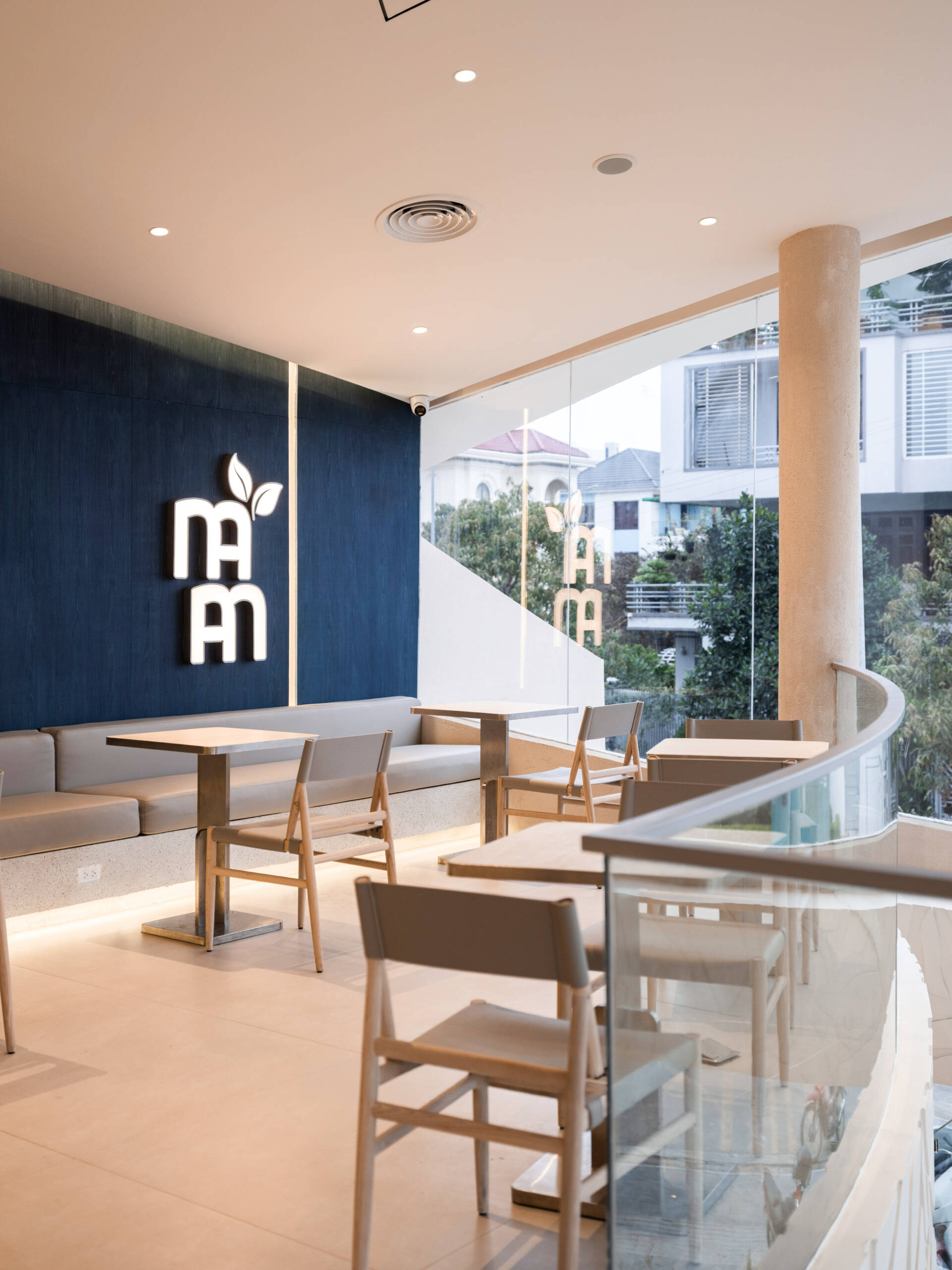 Inspired by the shape of a boat and featuring sweeping curved glass, soft flowing ceilings, and a calming neutral interior, this contemporary tea house celebrates one of Vietnam's most spectacular natural landscapes through architecture.