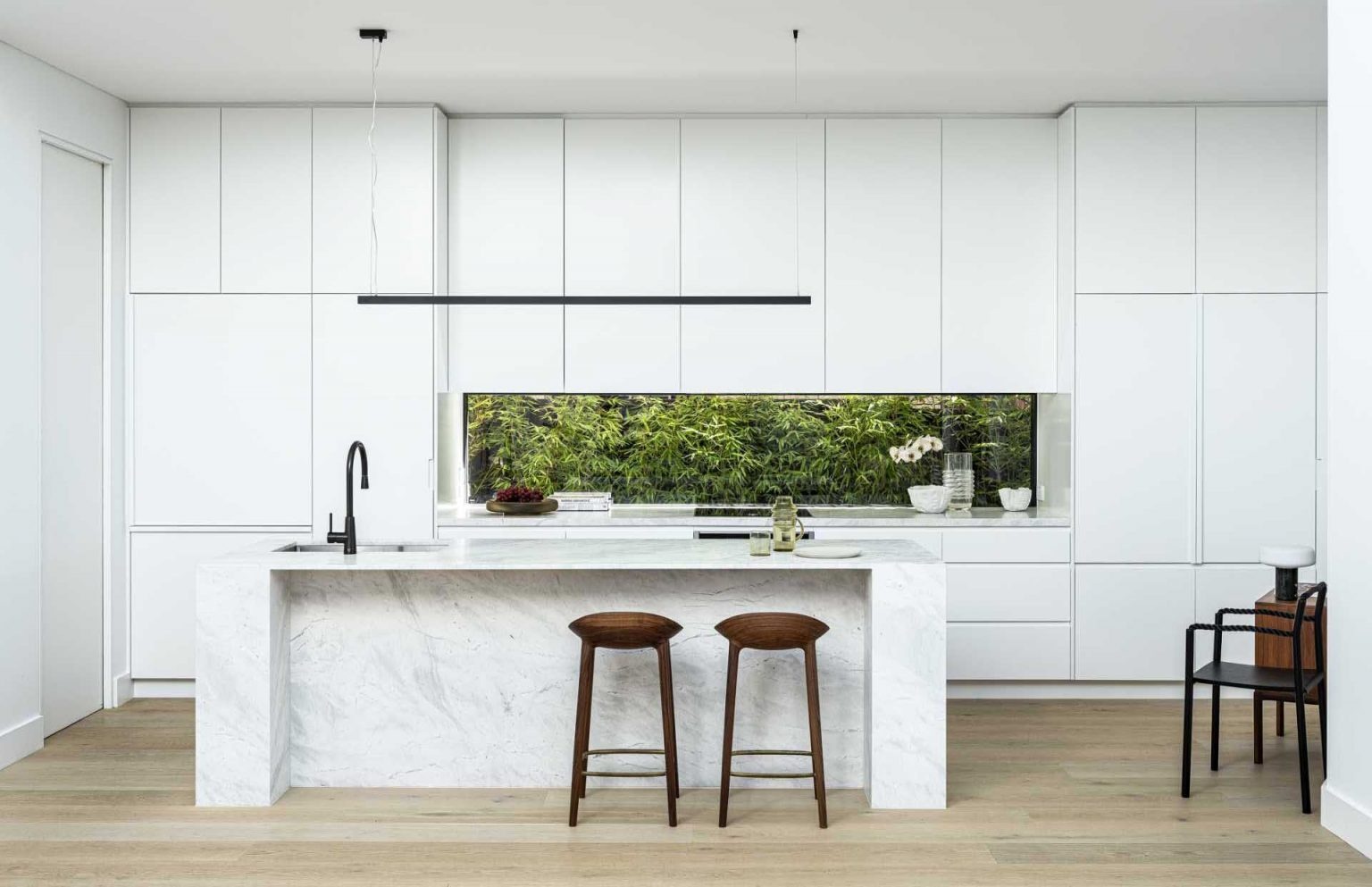 Minimalist white cabinetry, a window backsplash, and a practical island create a bright and functional kitchen.