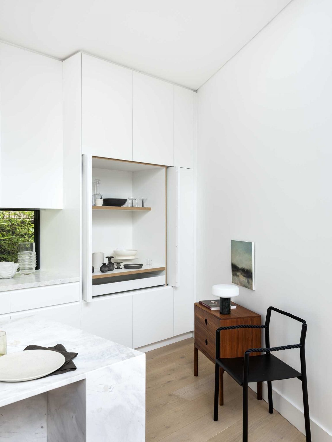Minimalist white cabinetry, a window backsplash, and a practical island create a bright and functional kitchen.
