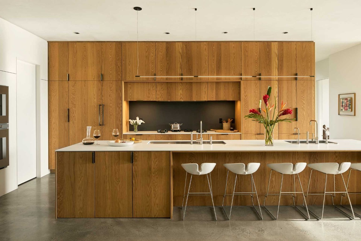 Tour an open-concept living kitchen where white oak cabinetry, Corian countertops, and modern furnishings create a welcoming family hub.