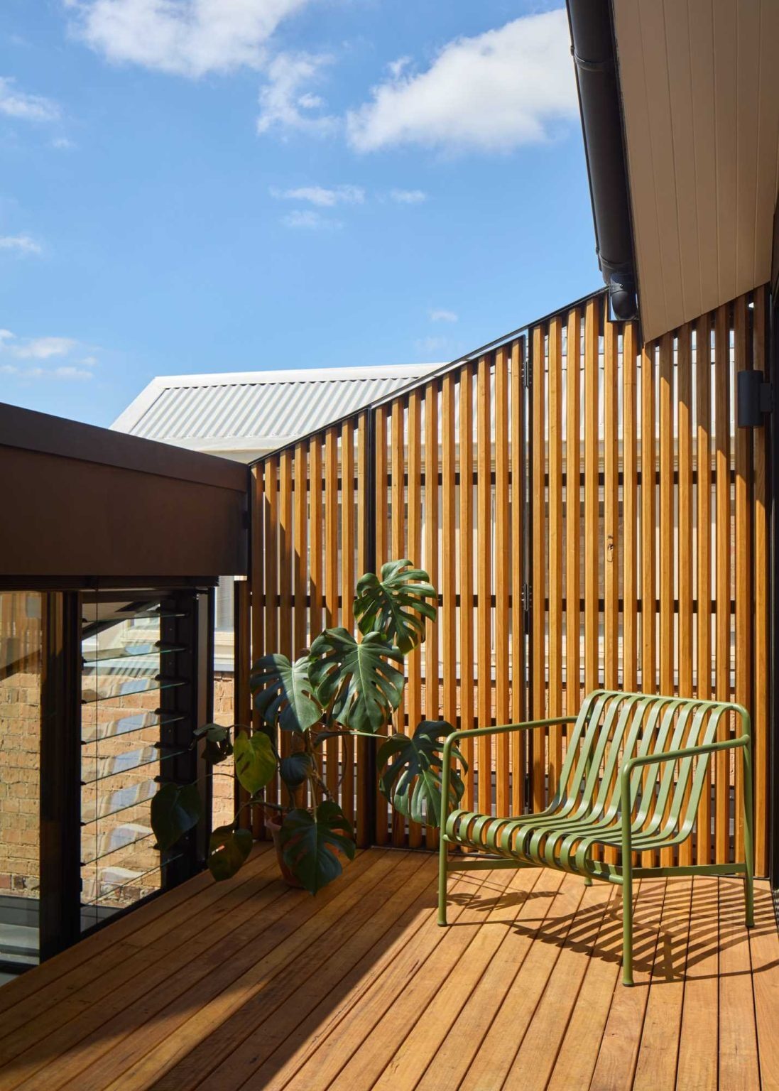 A plant-filled private balcony extends the bedroom outdoors and provides elevated views across rooftops and treetops.