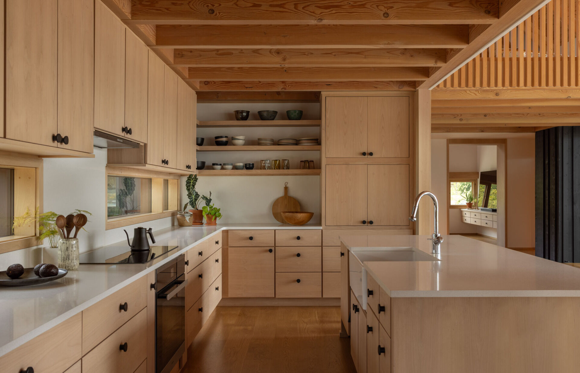 A warm and functional kitchen sits at the heart of this waterfront family home, surrounded by natural materials and inlet views.