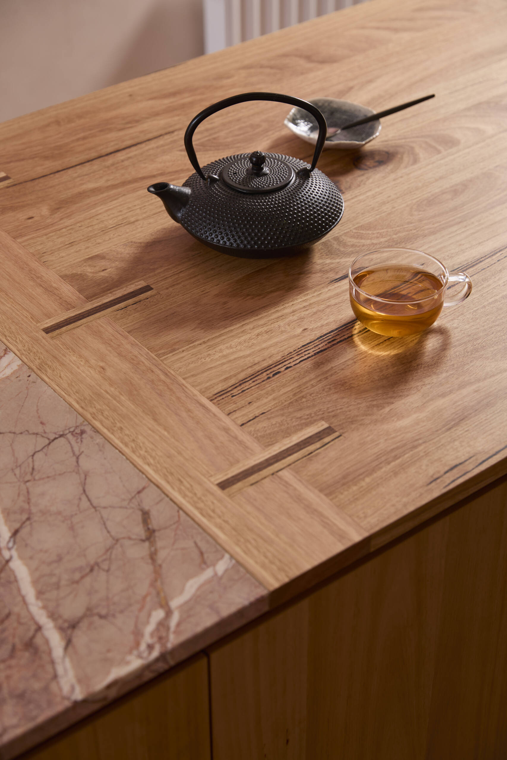 The kitchen forms the center of the home. Timber joinery, blush stone, handmade tiles, and copper detailing come together in a composition that feels tactile and expressive. It operates as both cooking space and social hub, opening directly to the lounge.