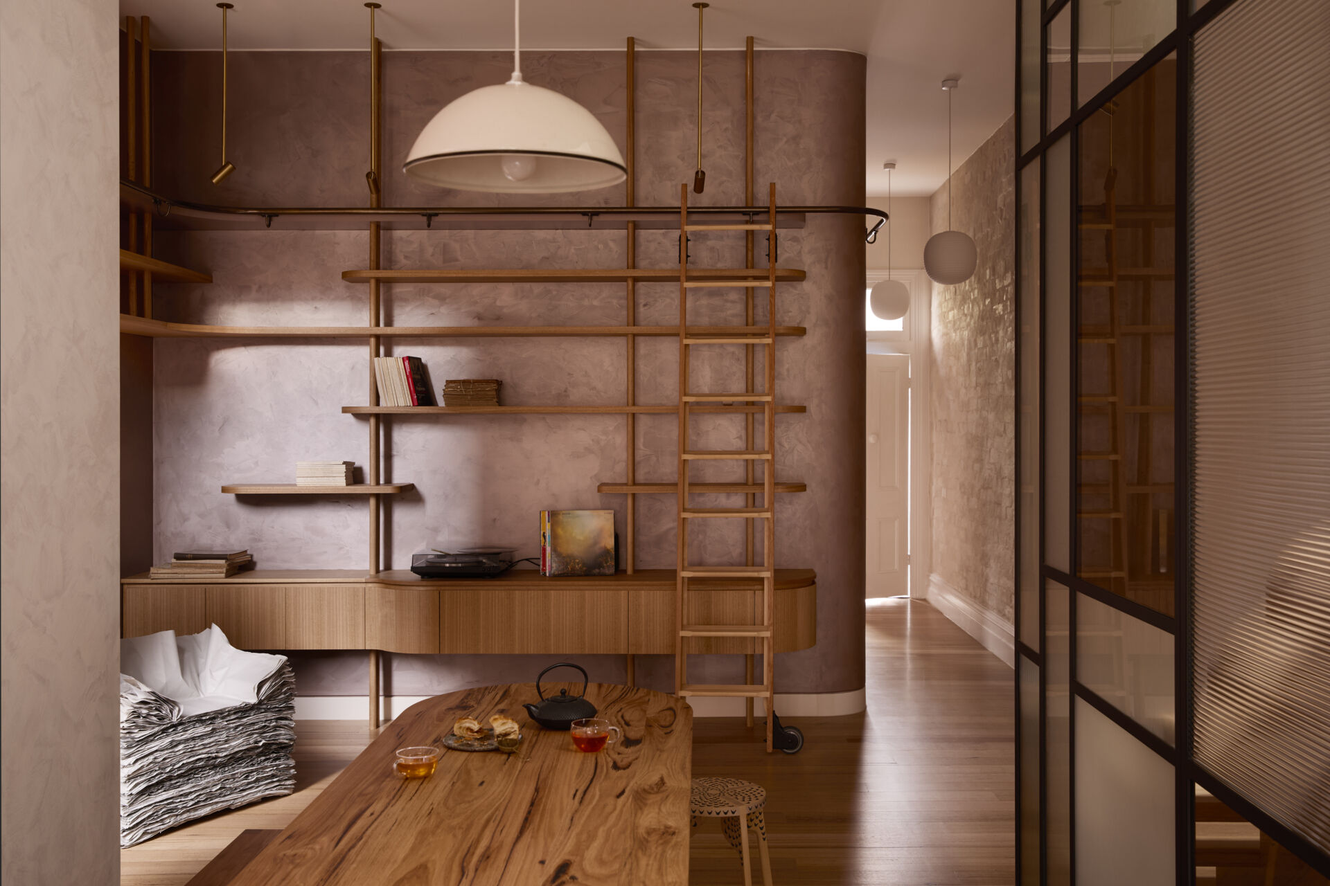 A warm and welcoming entry with custom shelving, a rolling library ladder, soft plaster walls, and pale timber floors. This cosy reading nook is full of clever storage ideas and relaxed interior styling inspiration.