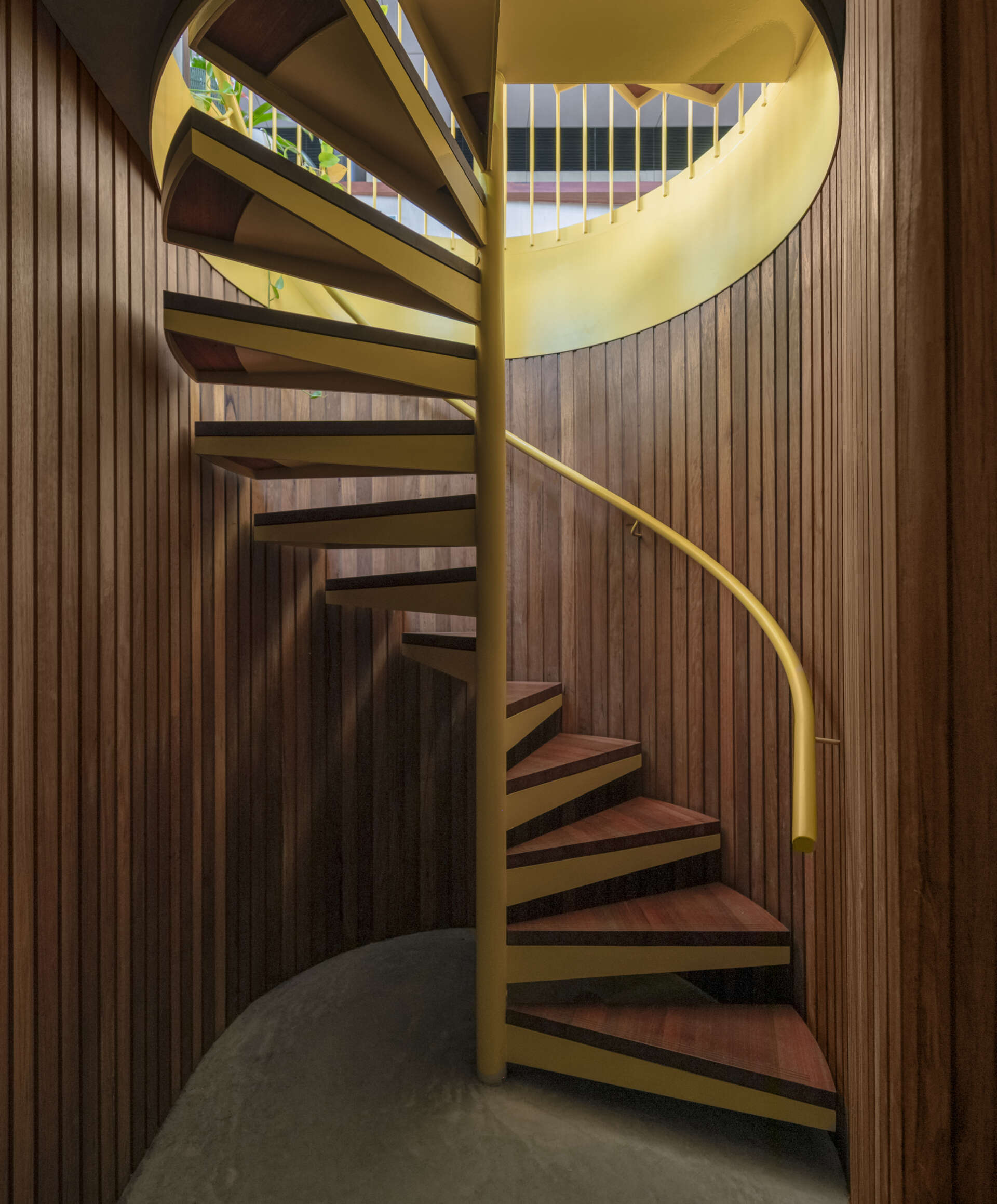 A bold yellow spiral staircase winds through three levels, becoming one of the most striking features of the entire home.