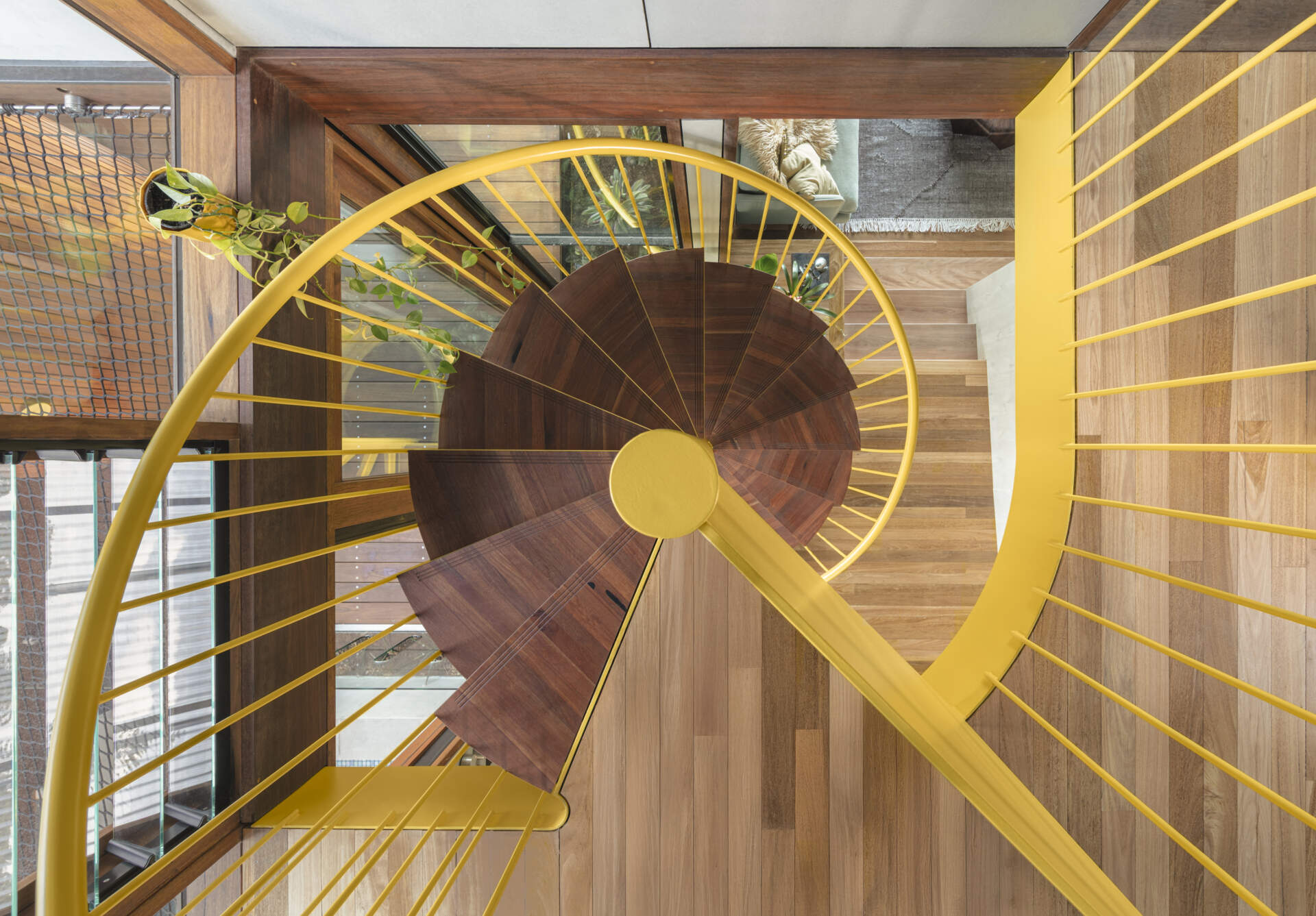 A bold yellow spiral staircase winds through three levels, becoming one of the most striking features of the entire home.