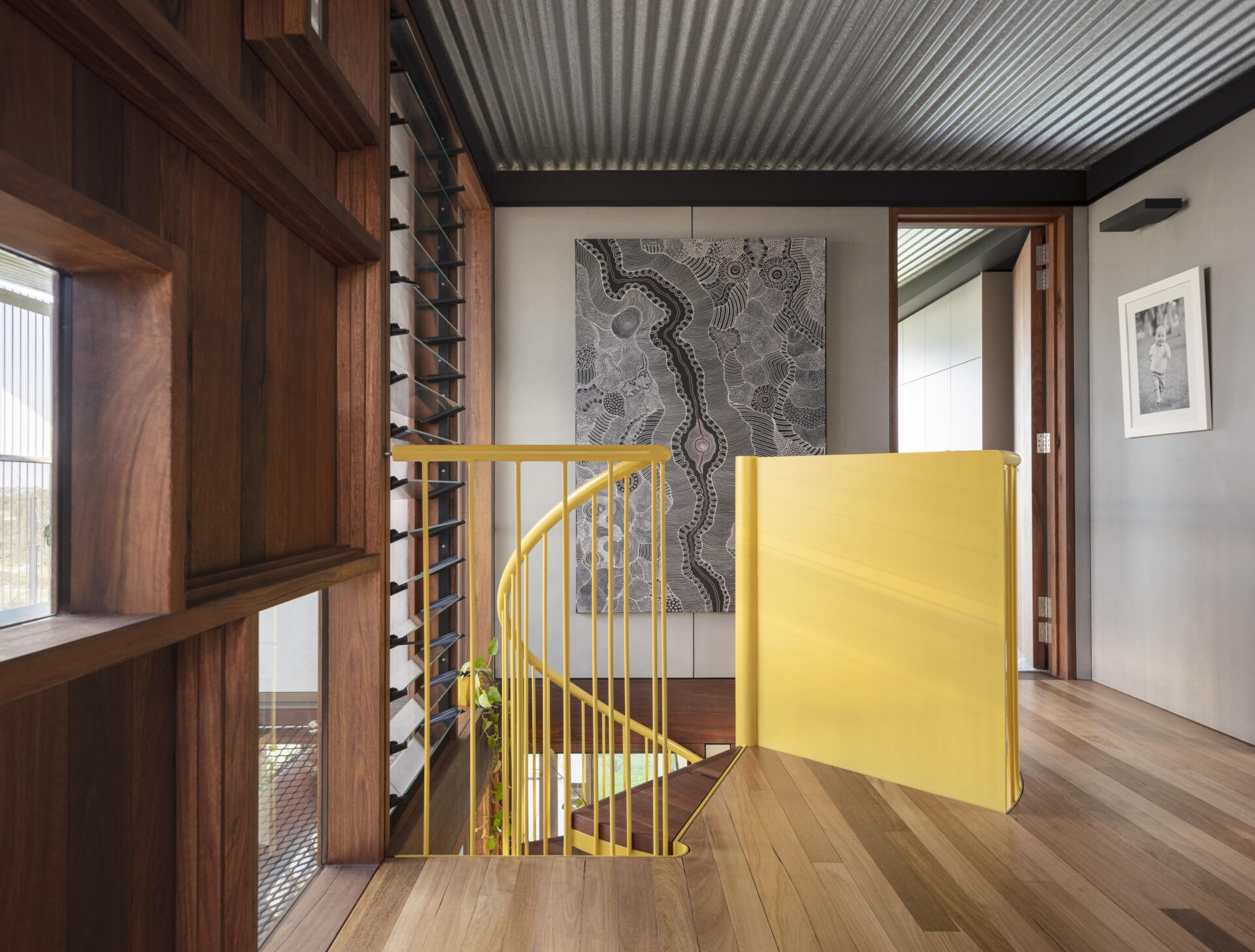 A bold yellow spiral staircase winds through three levels, becoming one of the most striking features of the entire home.
