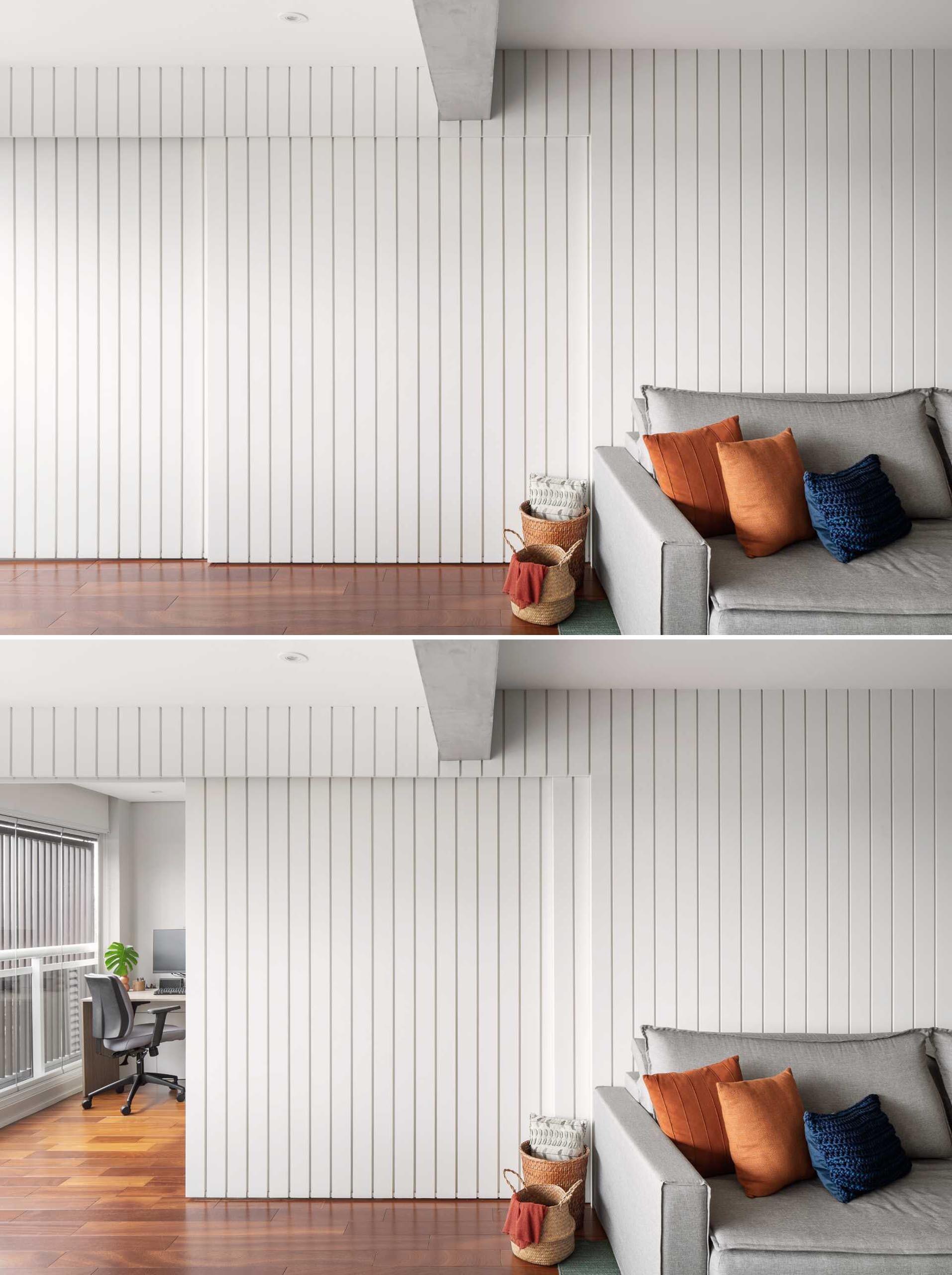 Discover how a striking white feature wall transforms this São Paulo apartment, hiding a home office and kitchen behind sleek sliding pocket doors while maintaining a clean, modern look.