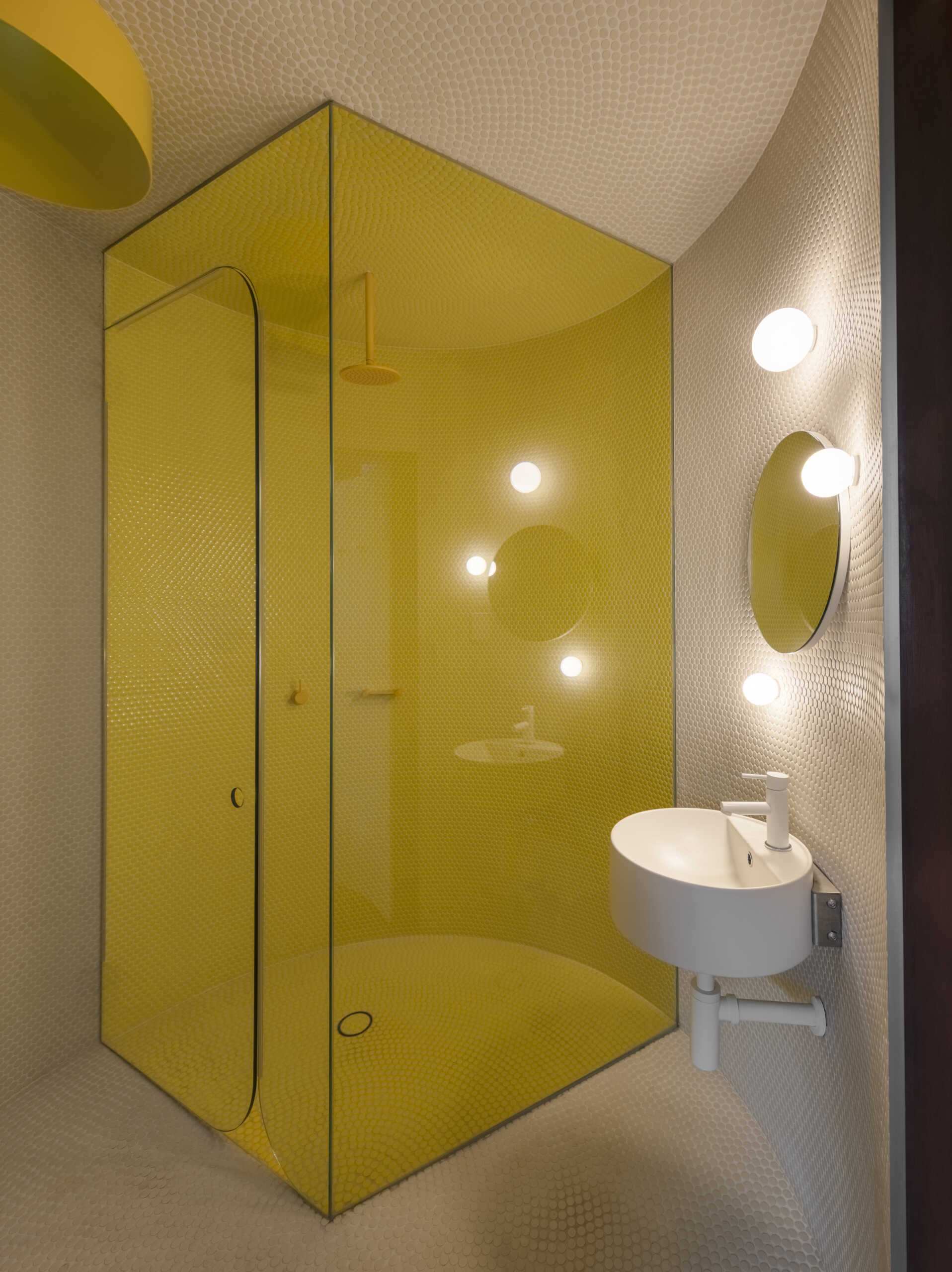 A secret steam room hidden behind a curved door features yellow penny tiles, a circular skylight, and playful architectural details.