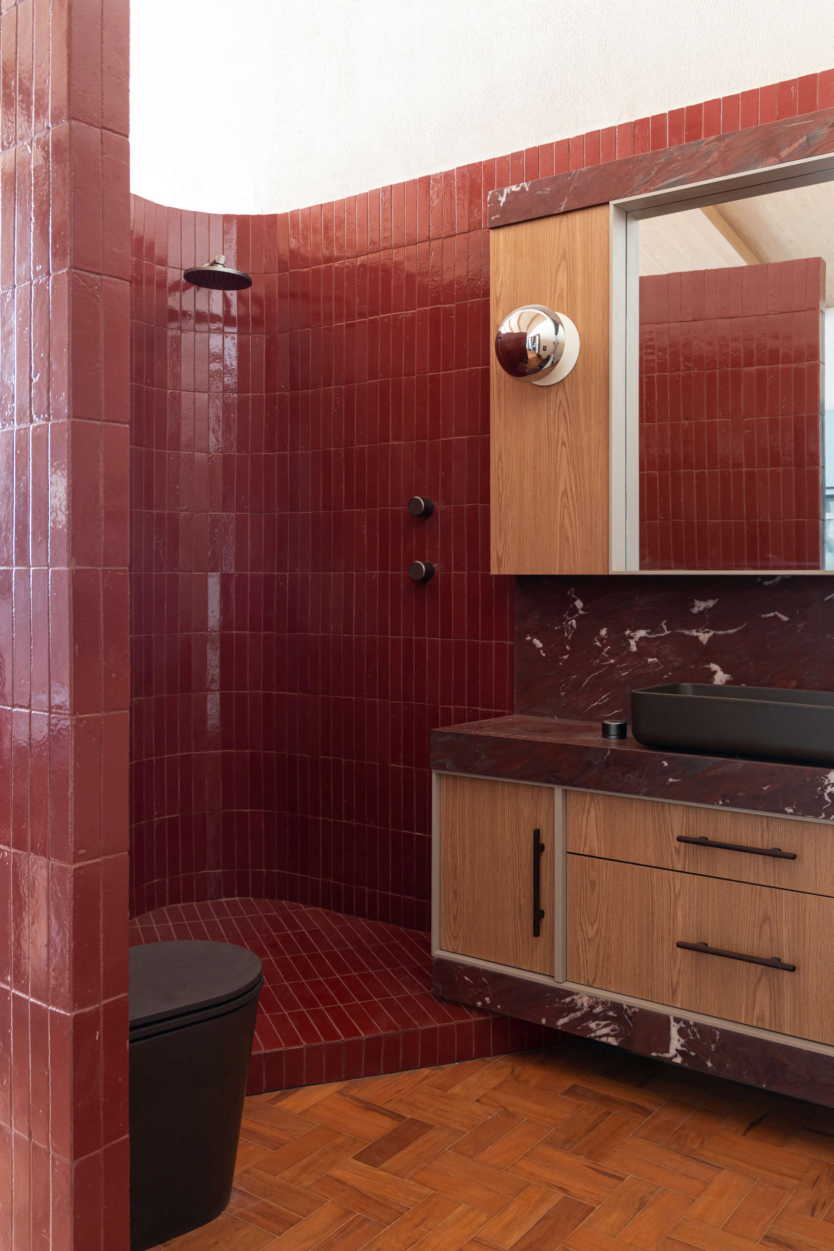 Red walls and ceilings, Bordeaux marble, and curved geometry create a bold bathroom design hidden inside the studio's iconic cylinder.