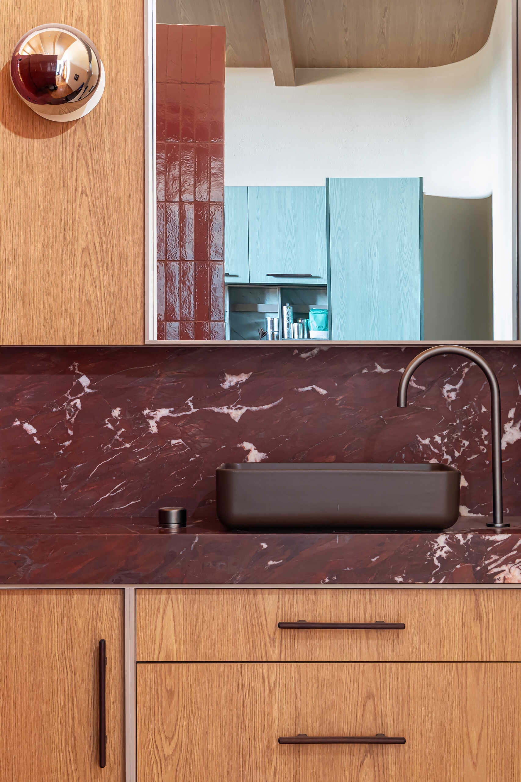 Red walls and ceilings, Bordeaux marble, and curved geometry create a bold bathroom design hidden inside the studio's iconic cylinder.