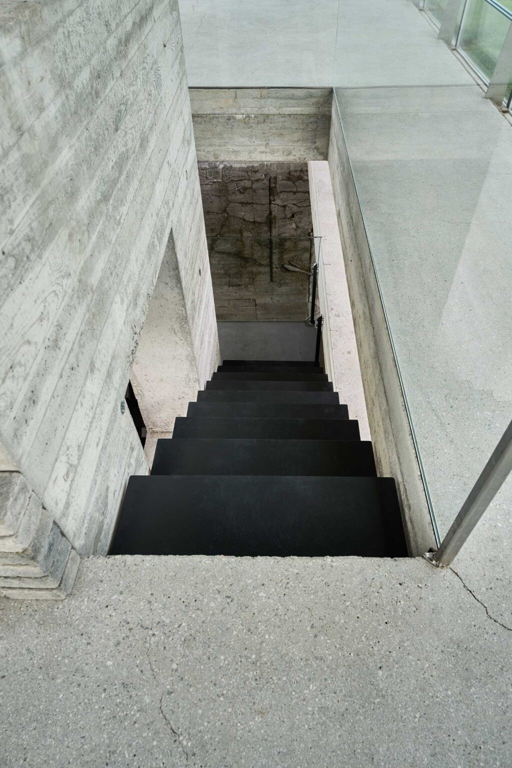 A staircase transforms the journey through this renovated bunker, leading visitors from solid concrete interiors into a bright glass pavilion above.