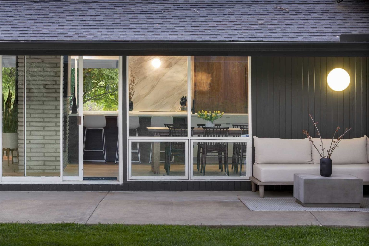 This Kansas City renovation begins with a striking dark exterior and a welcoming rear patio. Floor-to-ceiling windows connect indoor and outdoor spaces while highlighting the home's original mid-century architecture.