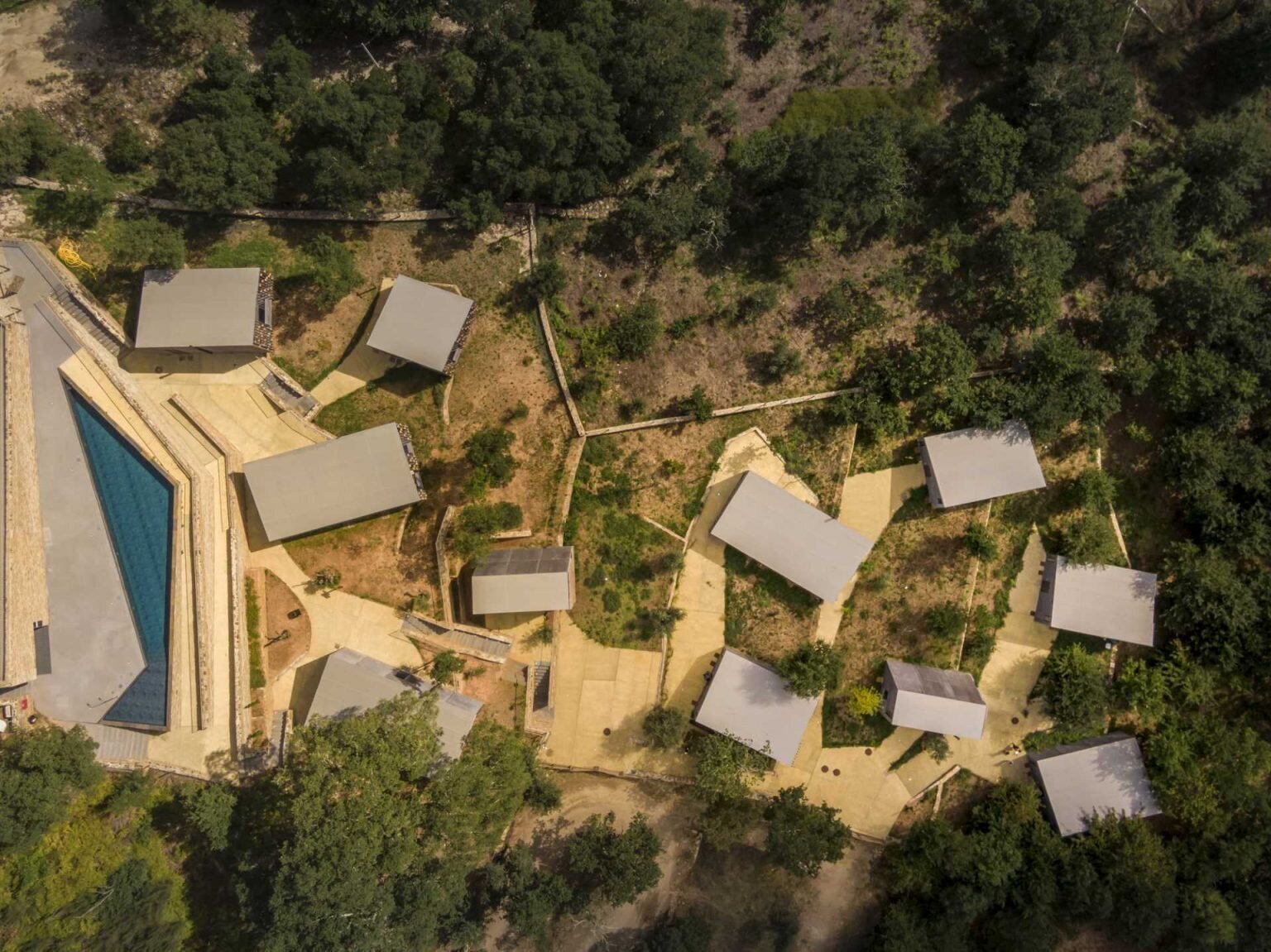 Eleven cabins in four unique designs are scattered across a Portuguese forest, preserving existing stone walls and mature trees. Their layout allows every home to enjoy open views of the surrounding woodland and river.