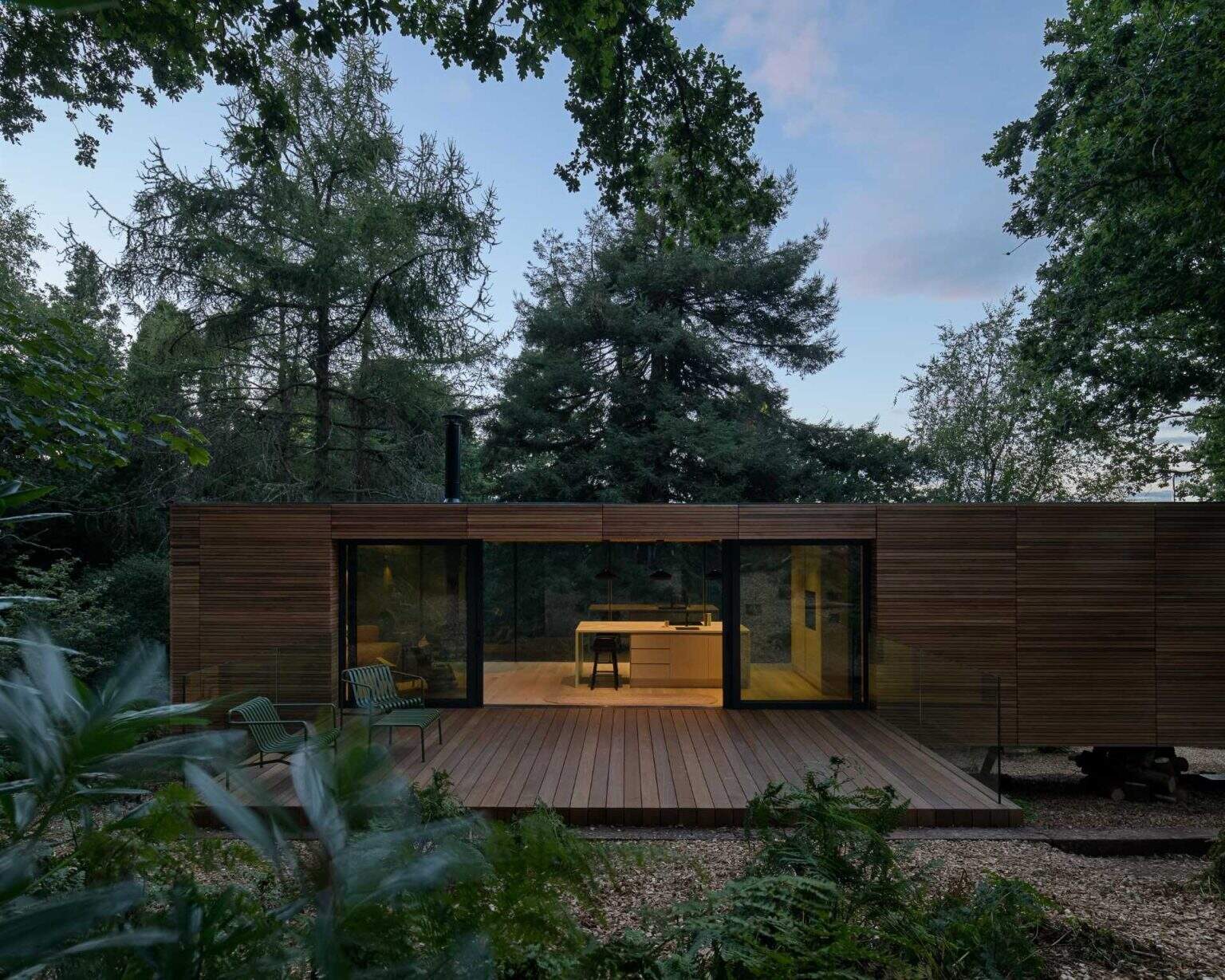 As night falls, this cedar lodge softly glows through the trees while remaining respectful of the surrounding protected landscape.