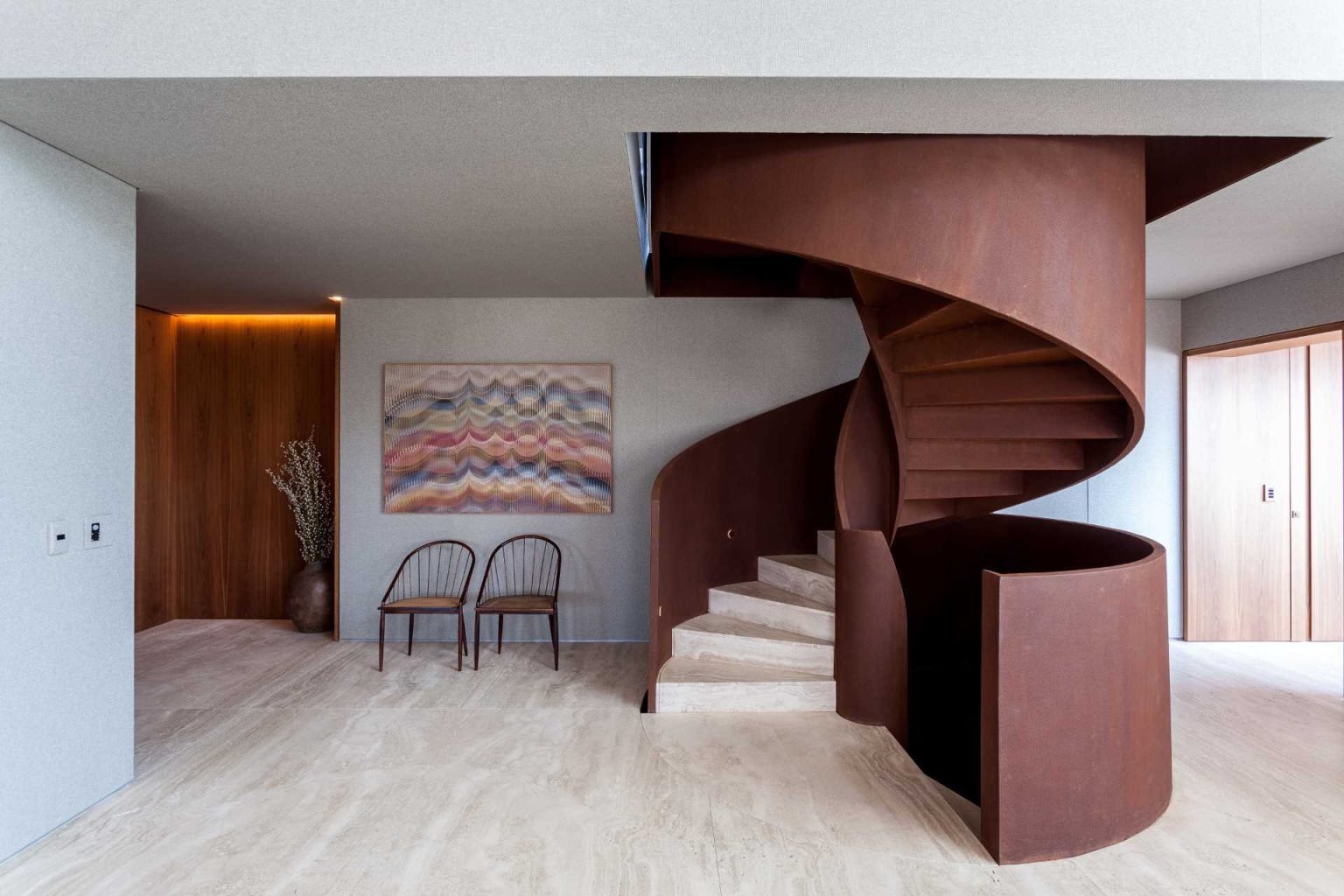 A dramatic spiral staircase crafted from Corten steel rises through this luxury penthouse, combining engineering innovation with sculptural beauty.