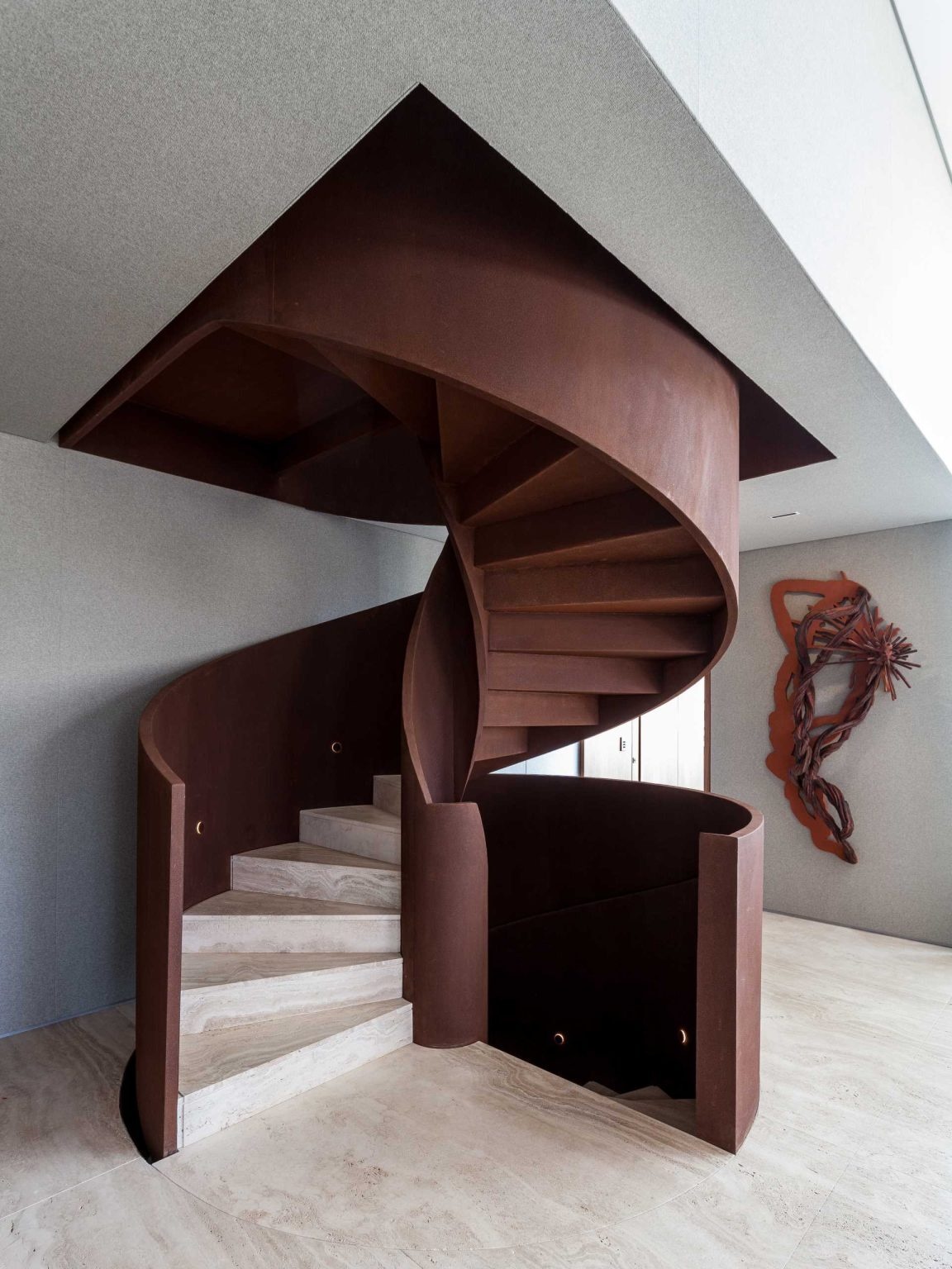 A dramatic spiral staircase crafted from Corten steel rises through this luxury penthouse, combining engineering innovation with sculptural beauty.