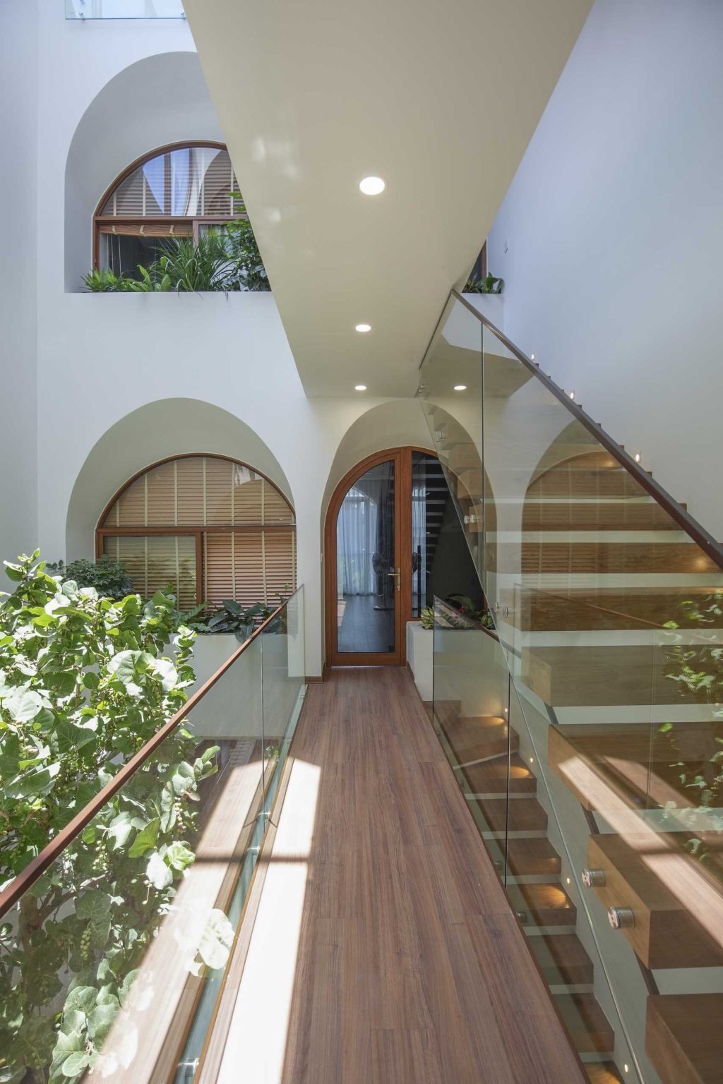 A dramatic central atrium filled with plants, bridges, skylights, and a koi pond brings natural light and greenery to every level of this Vietnam home.