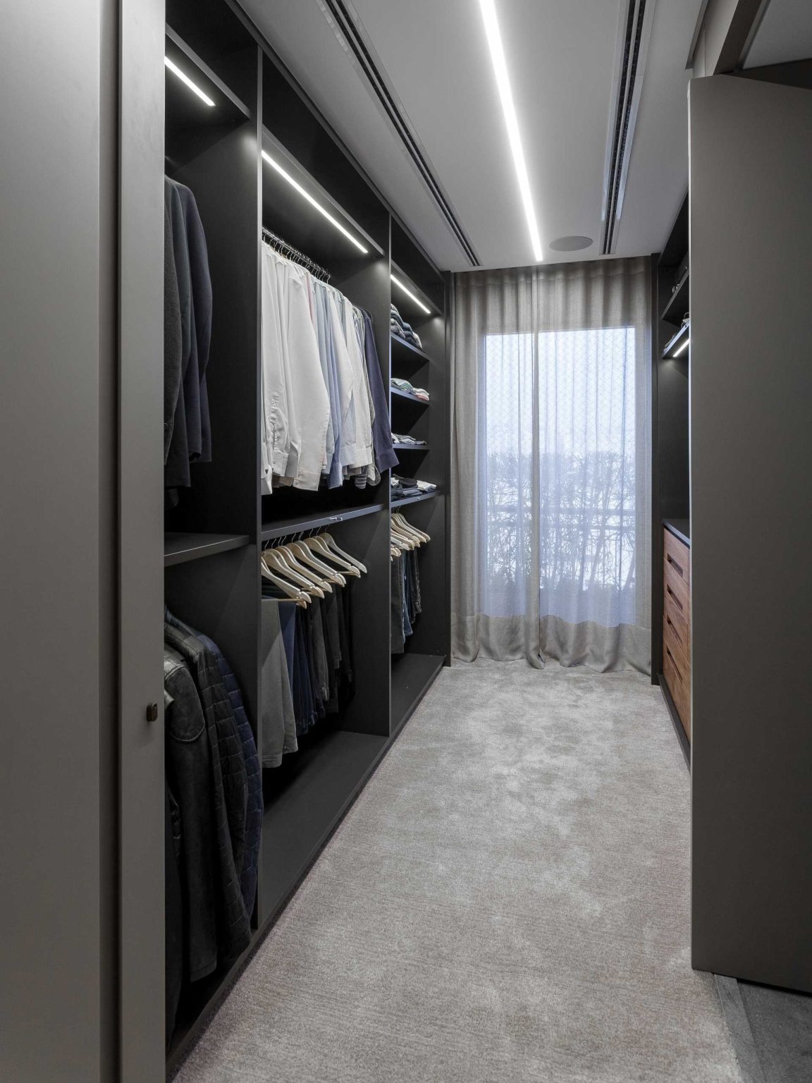 A luxury primary bedroom combines hidden lighting, custom millwork, and spacious walk-in closets to create a sophisticated and highly functional private suite.