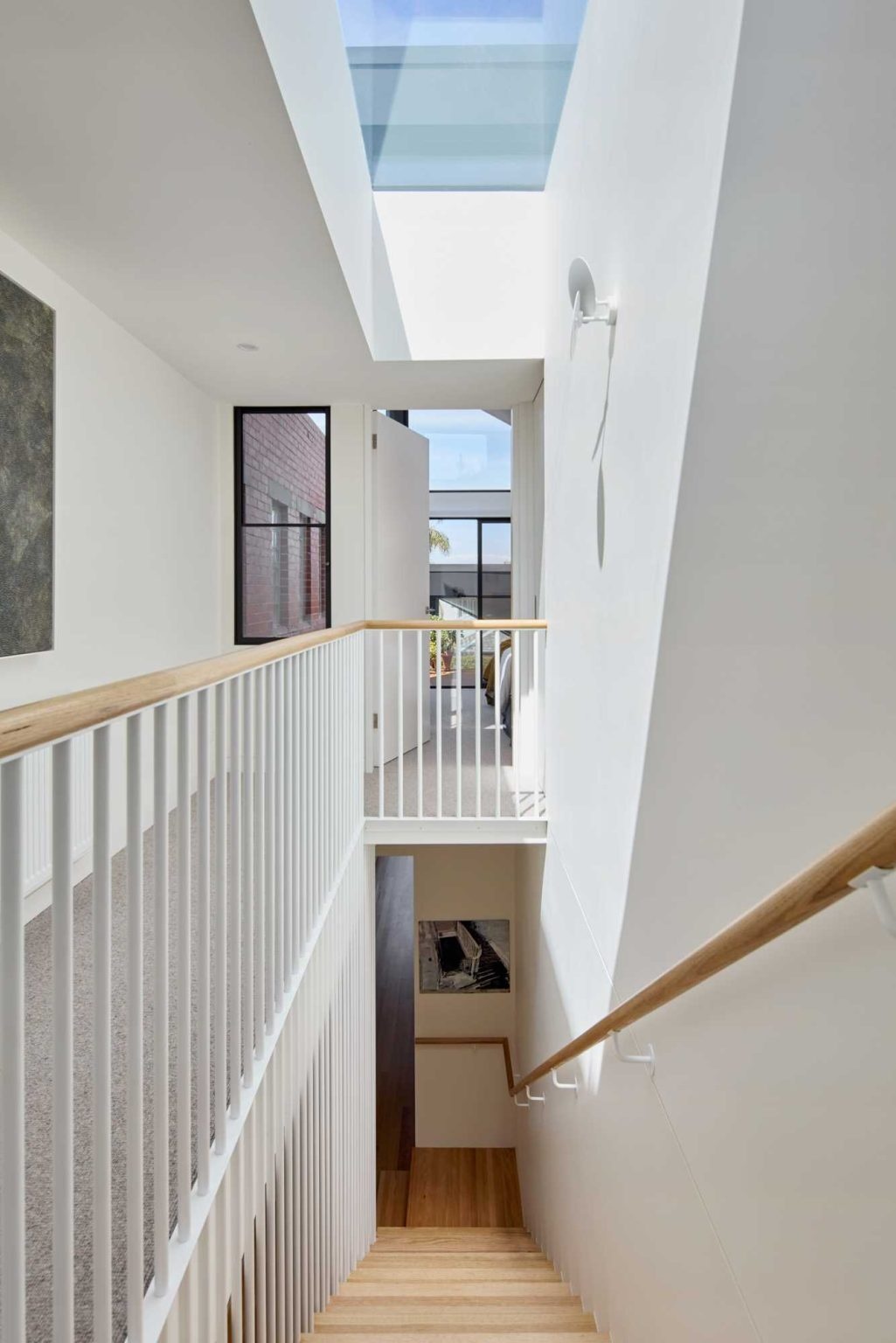 Timber and white stairs with built-in shelving create a stylish transition between the heritage home and its modern extension.