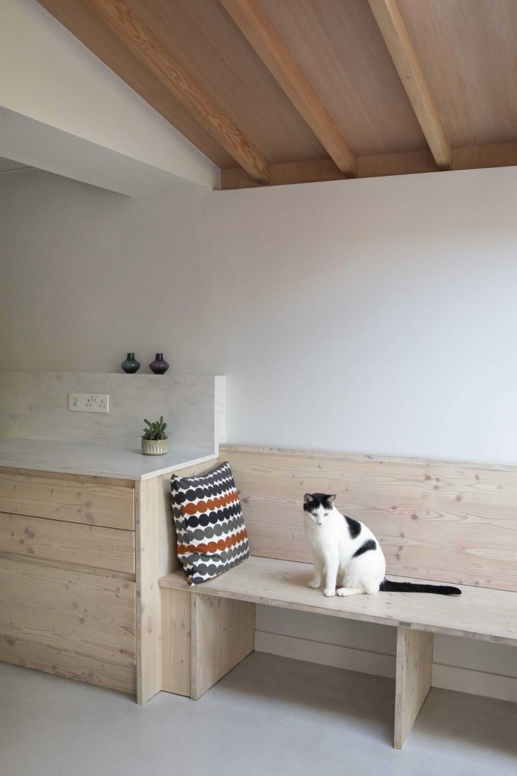 Exposed timber beams, soft white walls, and light micro cement flooring create a warm and contemporary interior palette. Natural materials bring texture and brightness while allowing the architecture and garden views to take centre stage.